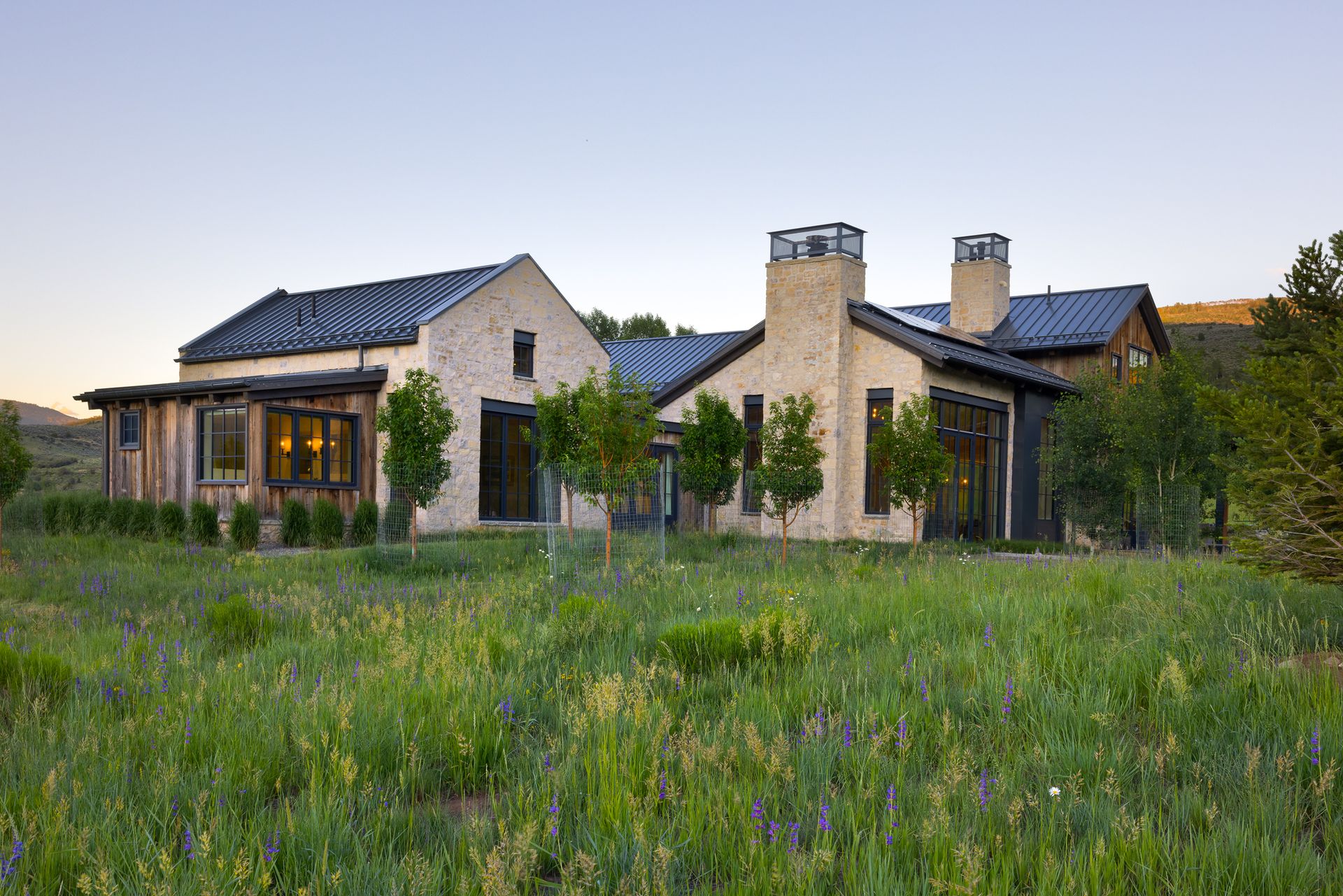 A large house is sitting in the middle of a grassy field.