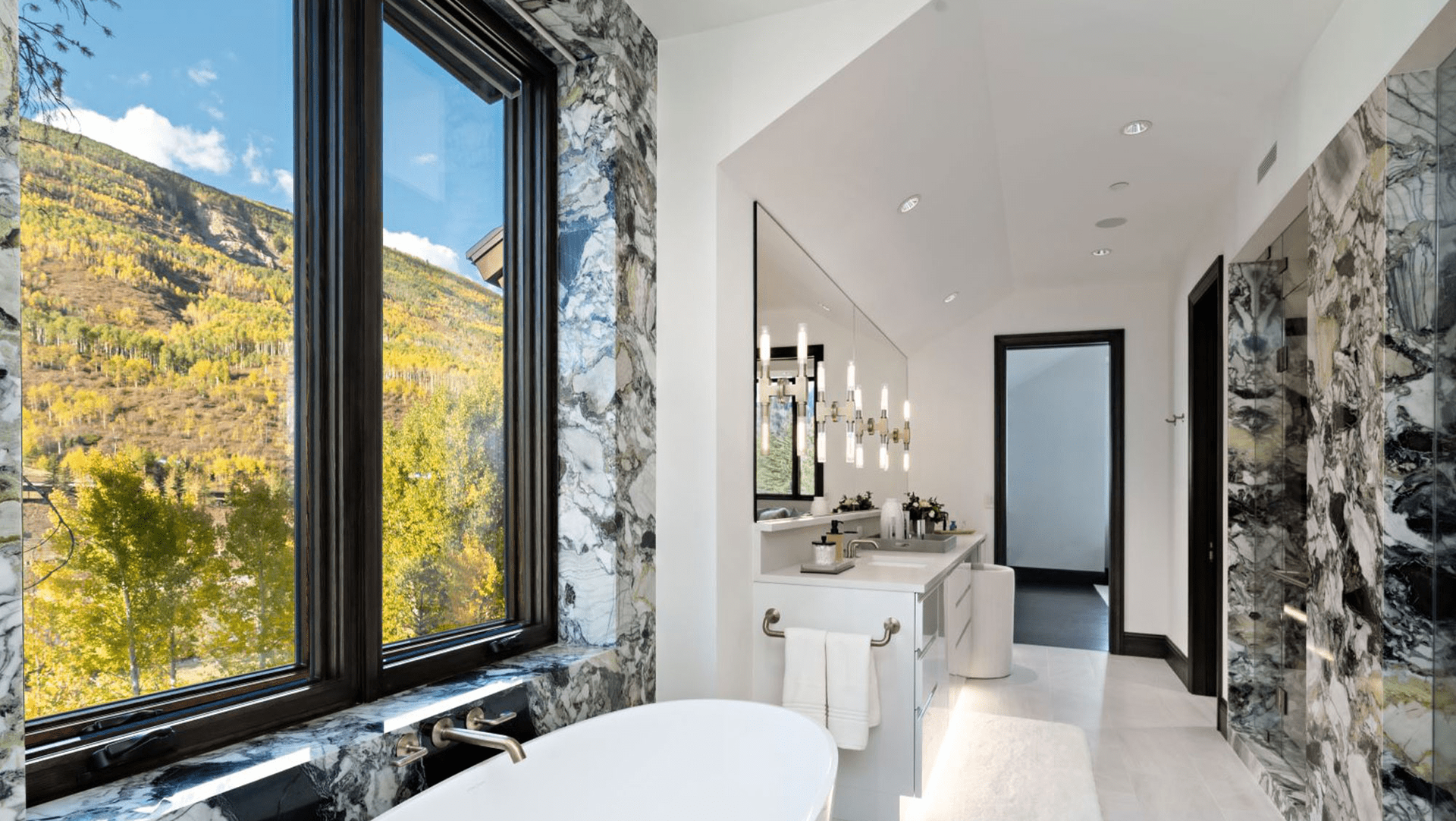A bathroom with a tub , sink , mirror and window.