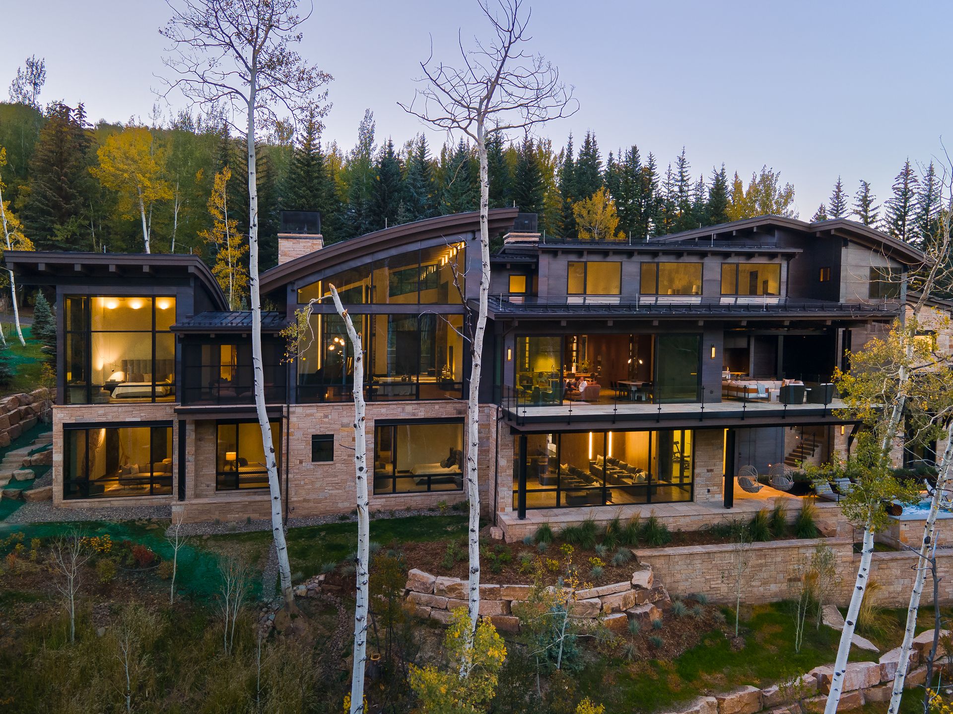 A large house sits on top of a hill surrounded by trees