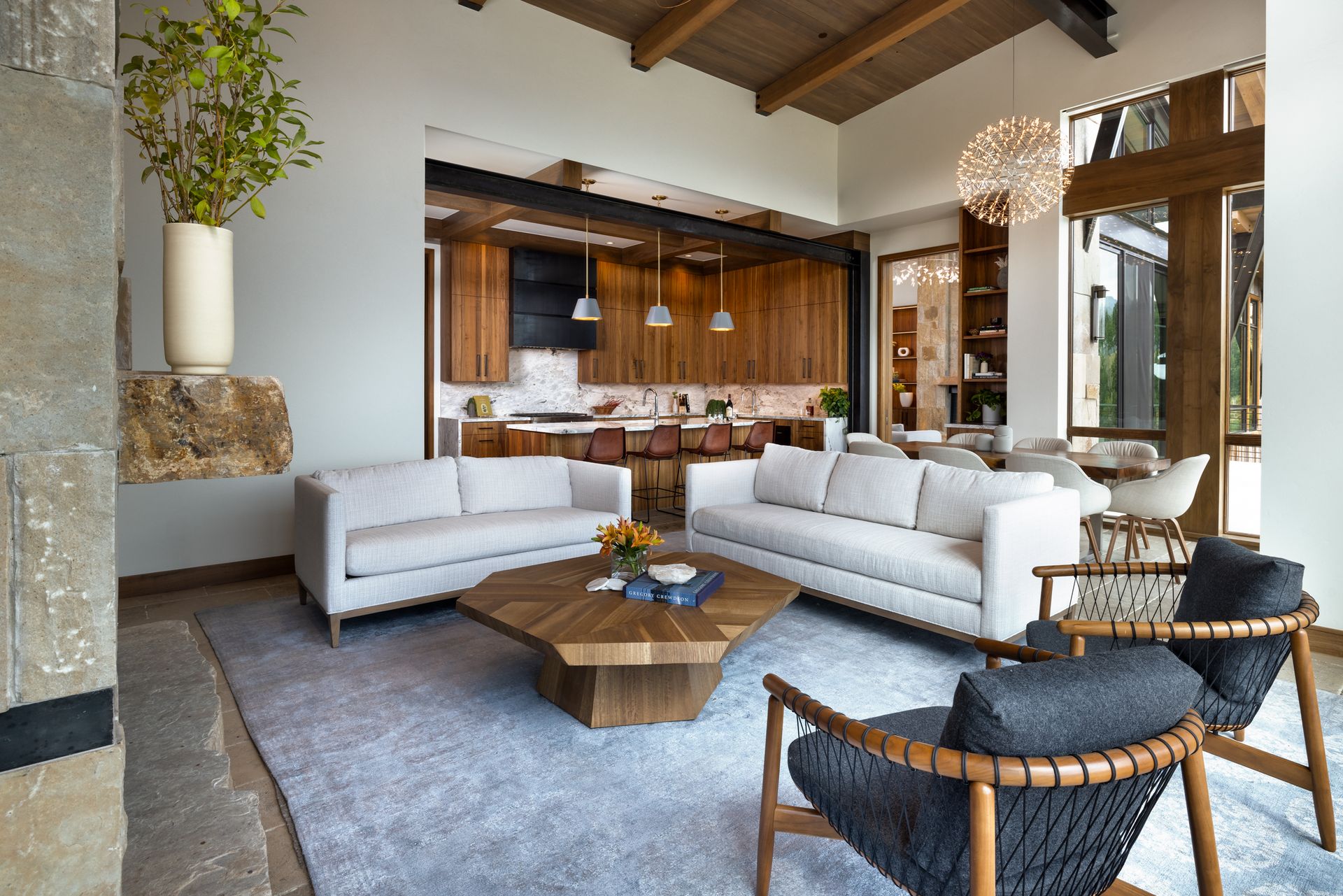 A living room with two couches , two chairs , a coffee table and a fireplace.