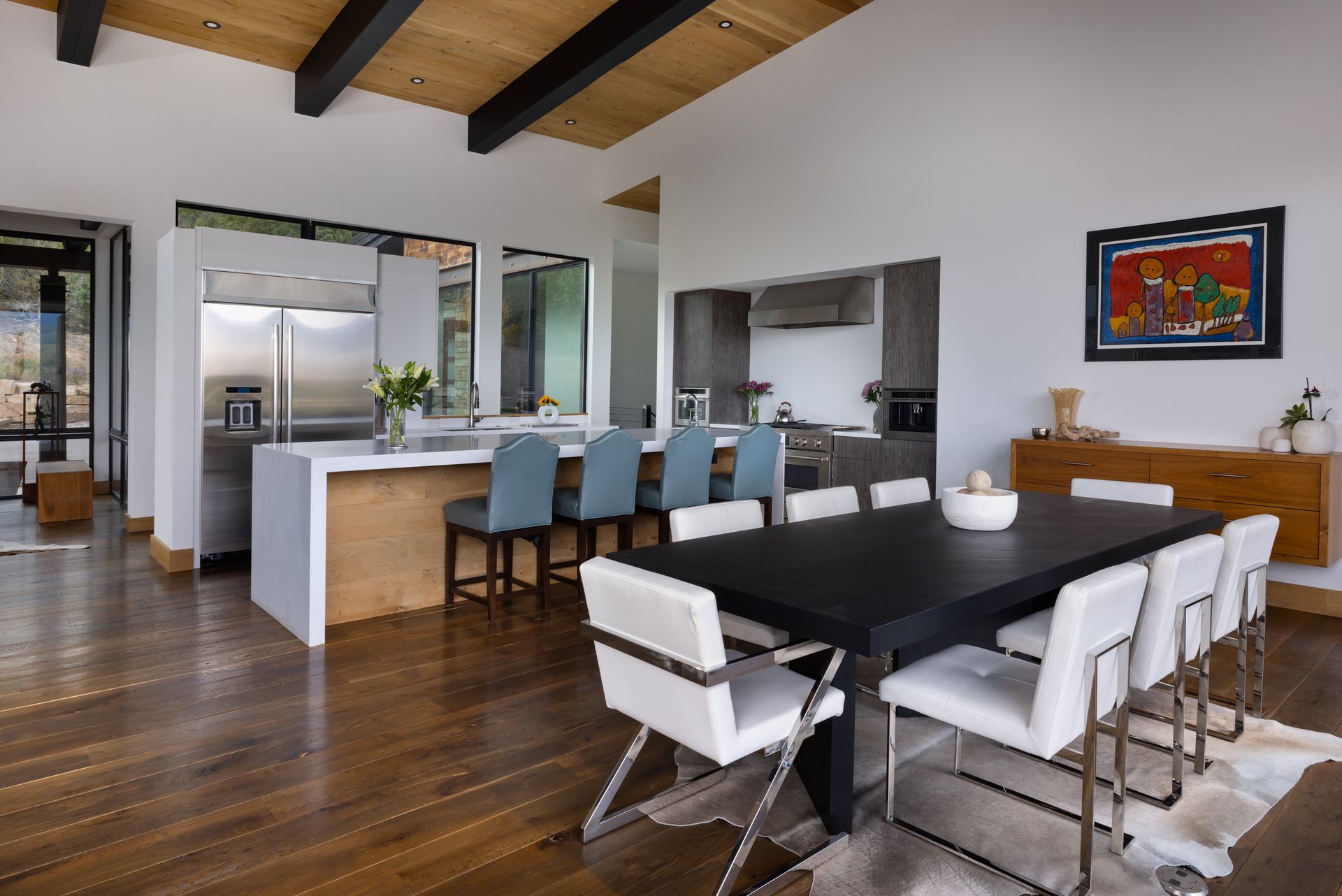 A dining room table with white chairs and a kitchen in the background.