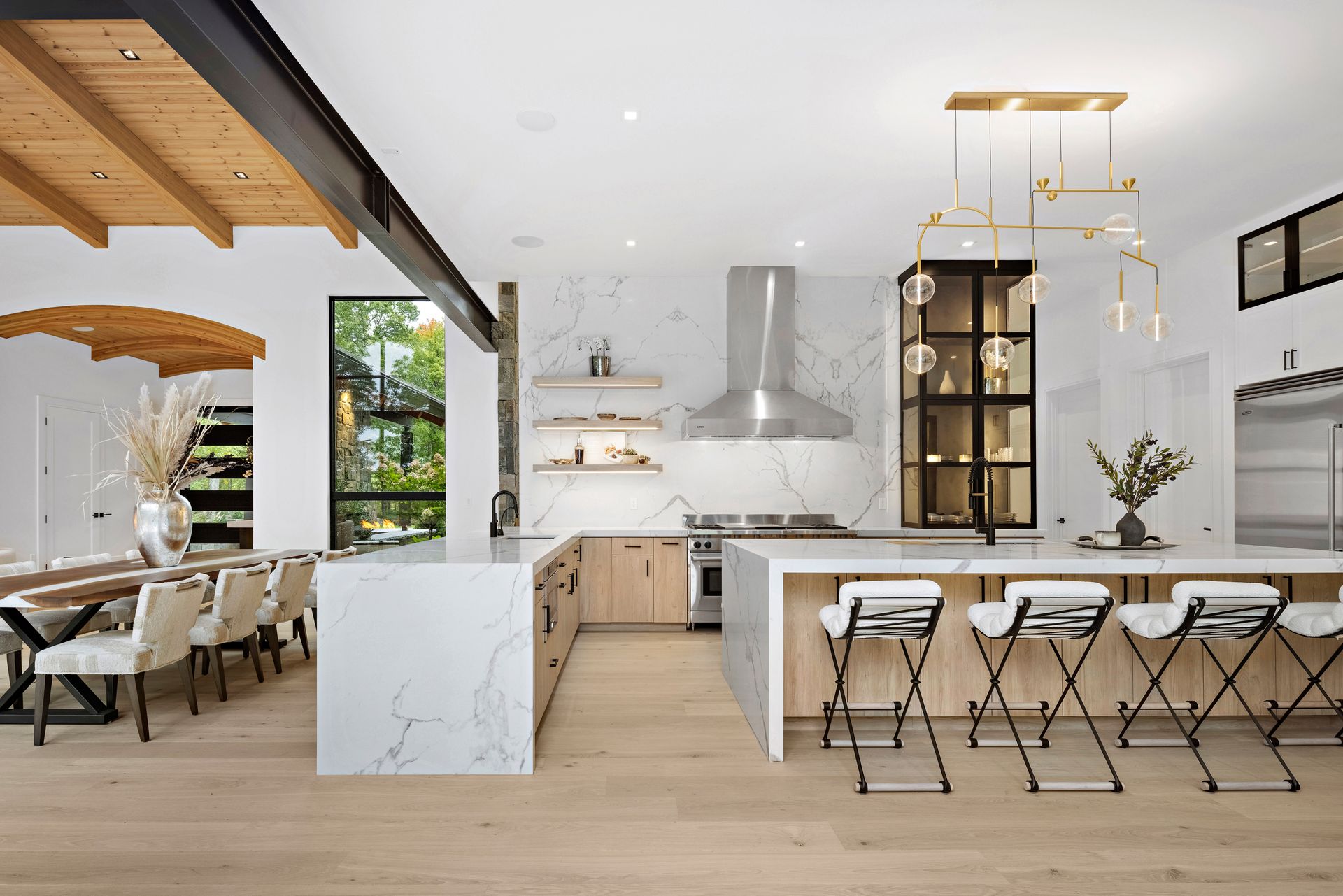 A kitchen with a large island and stools and a dining room in the background.