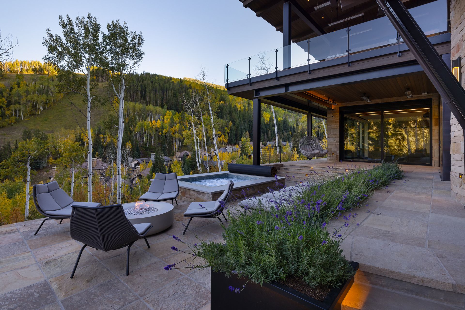 A large house with a patio area with chairs and a fire pit.