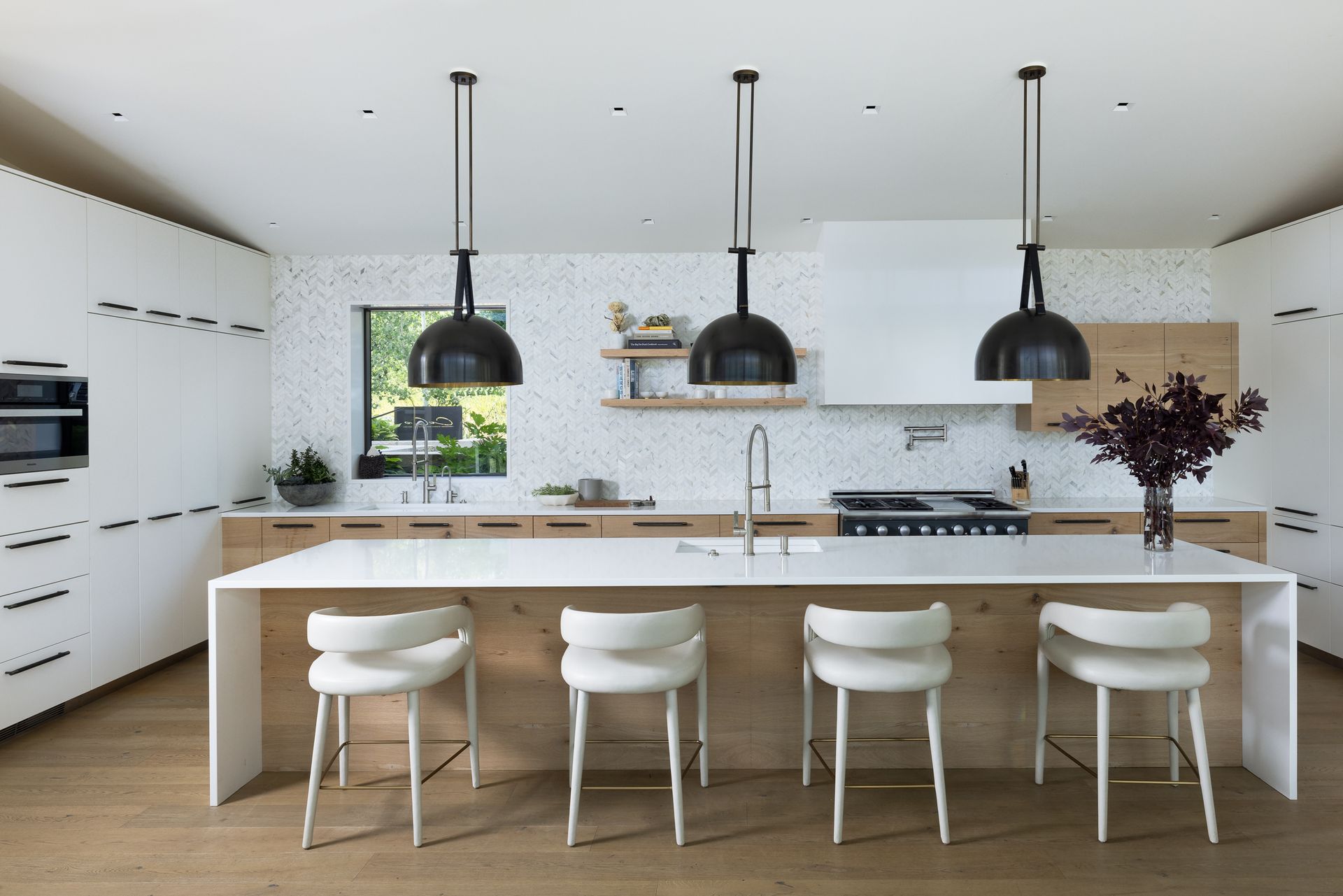 A kitchen with white cabinets , wooden cabinets , and a large island.