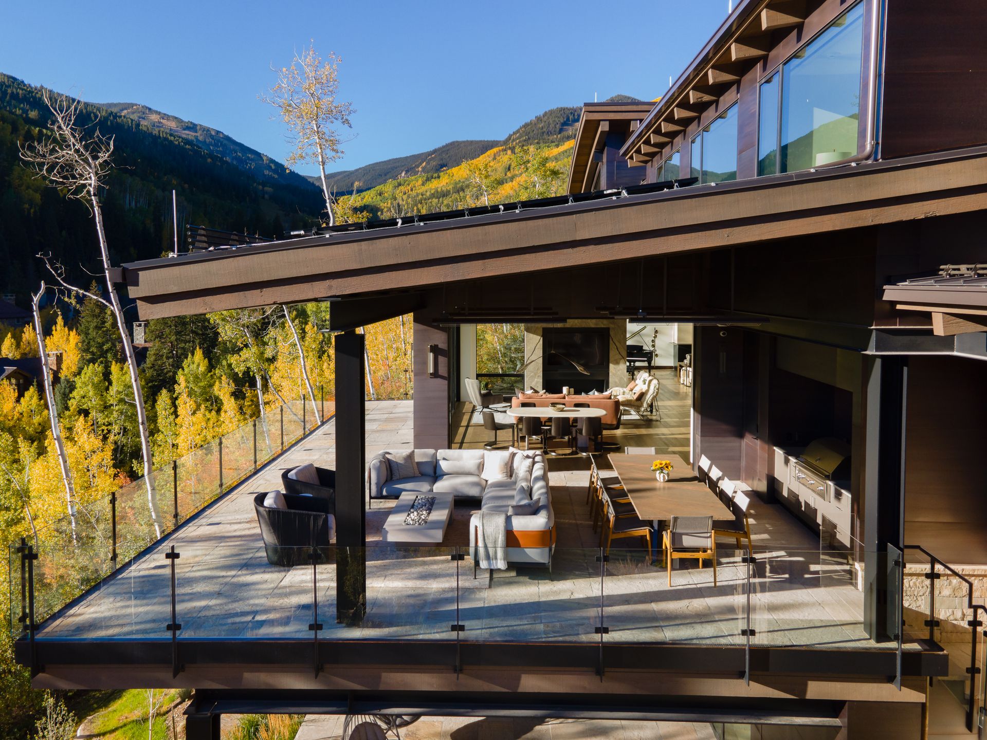 An aerial view of a house with a large deck and mountains in the background.
