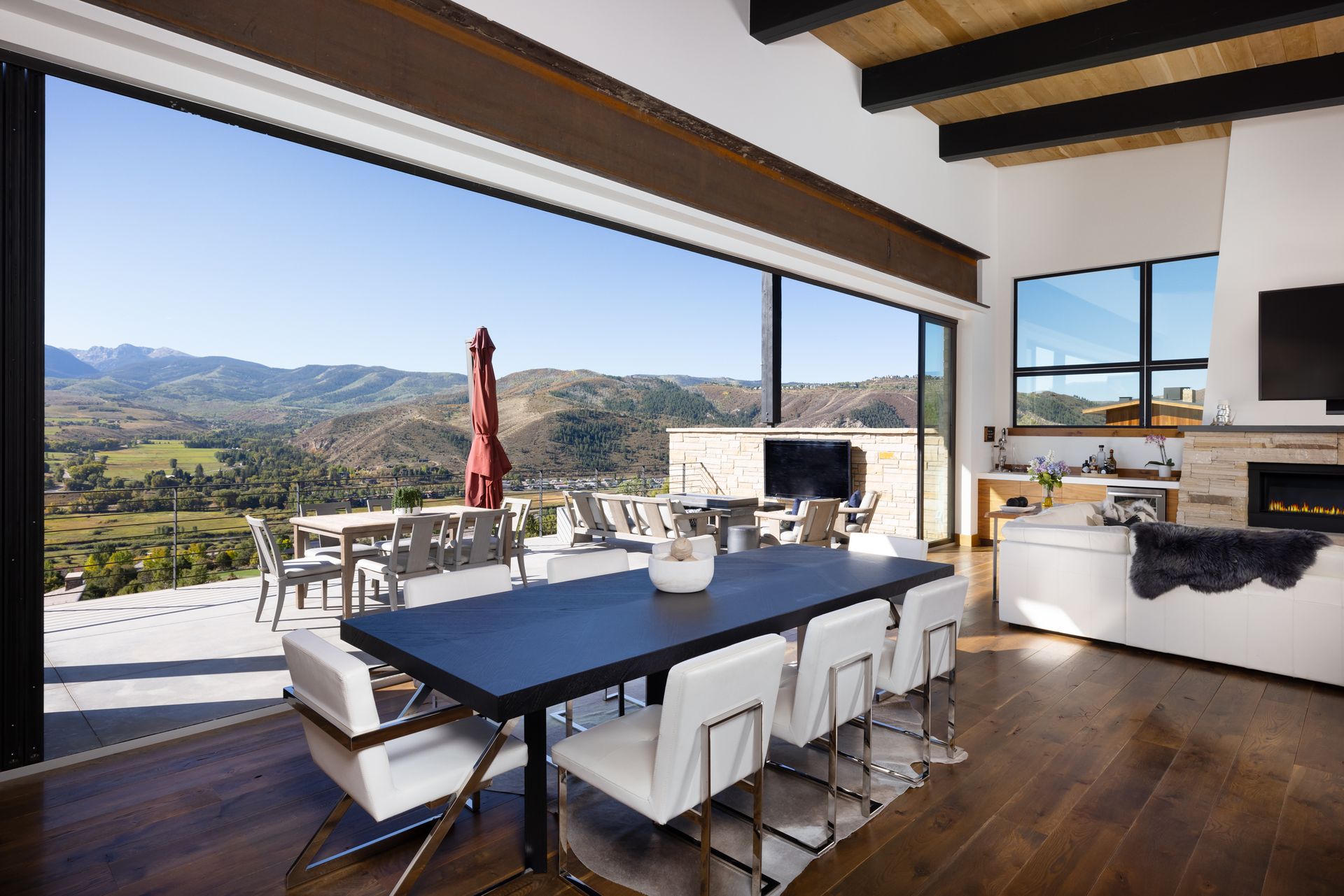 A dining room with a table and chairs and a view of mountains