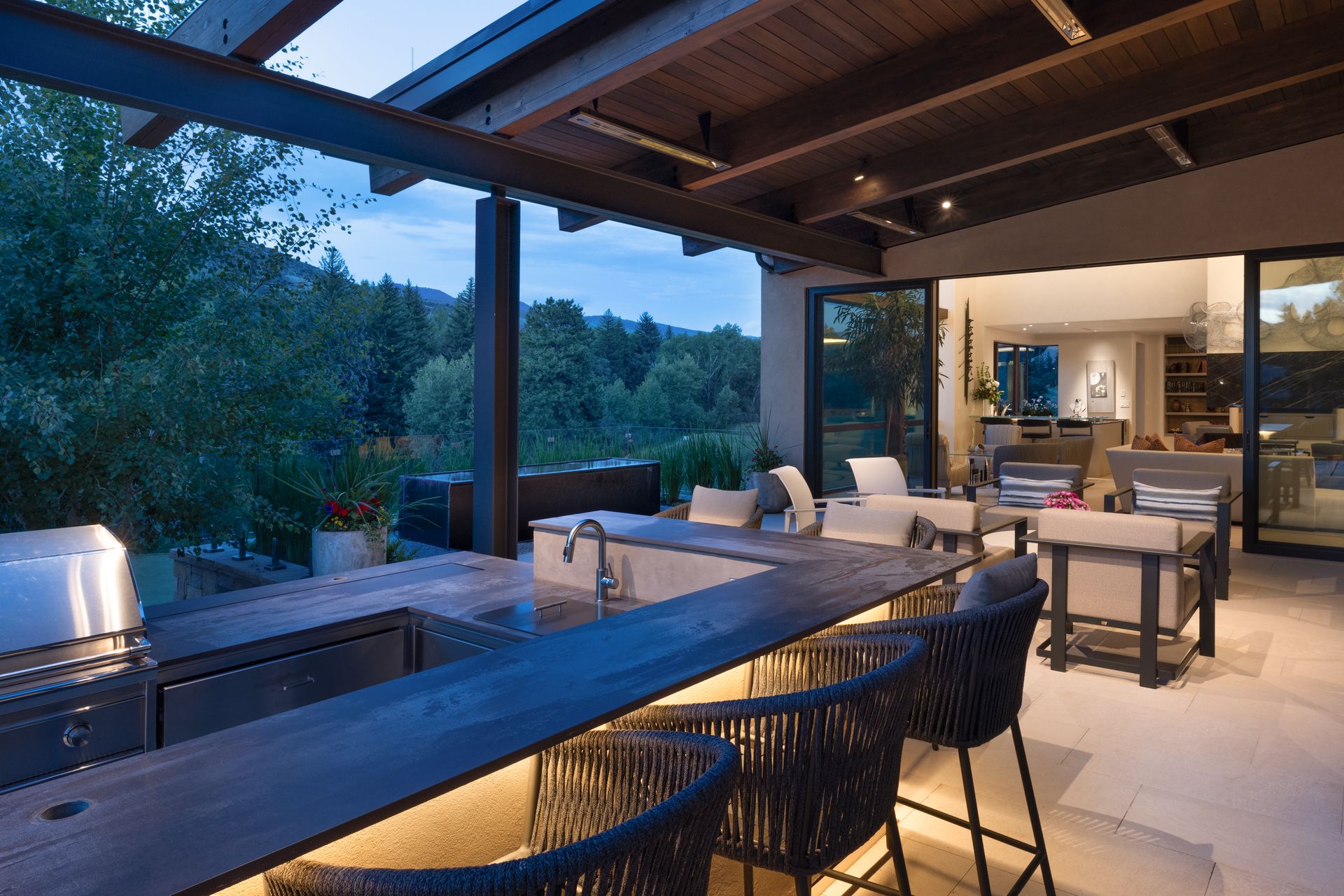 A patio with a large table and chairs and a stainless steel grill.