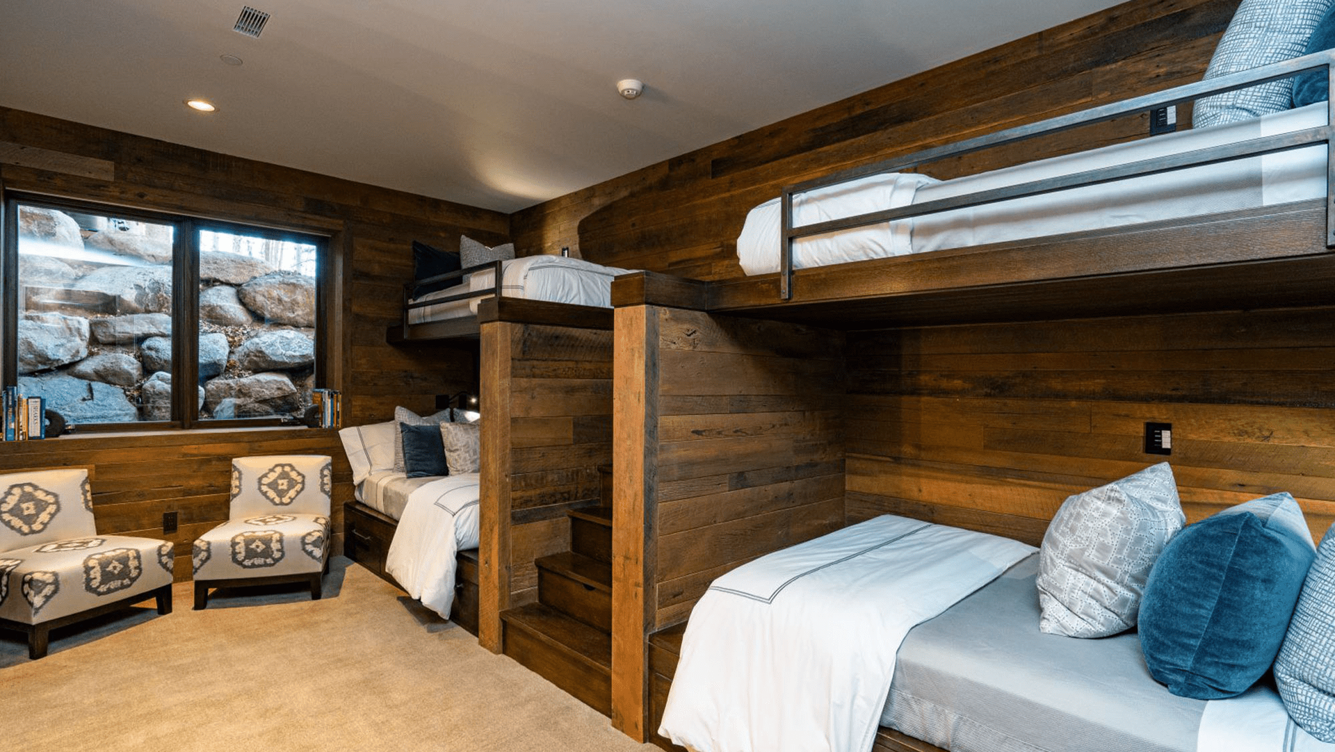 A bedroom with bunk beds , chairs and a window.