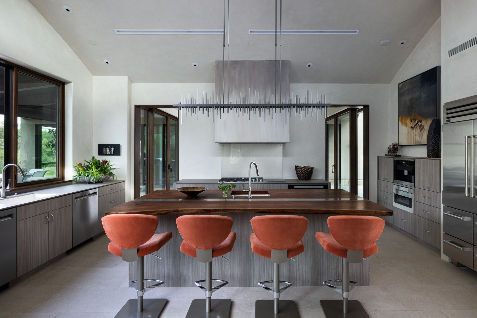 A kitchen with a large island and orange chairs