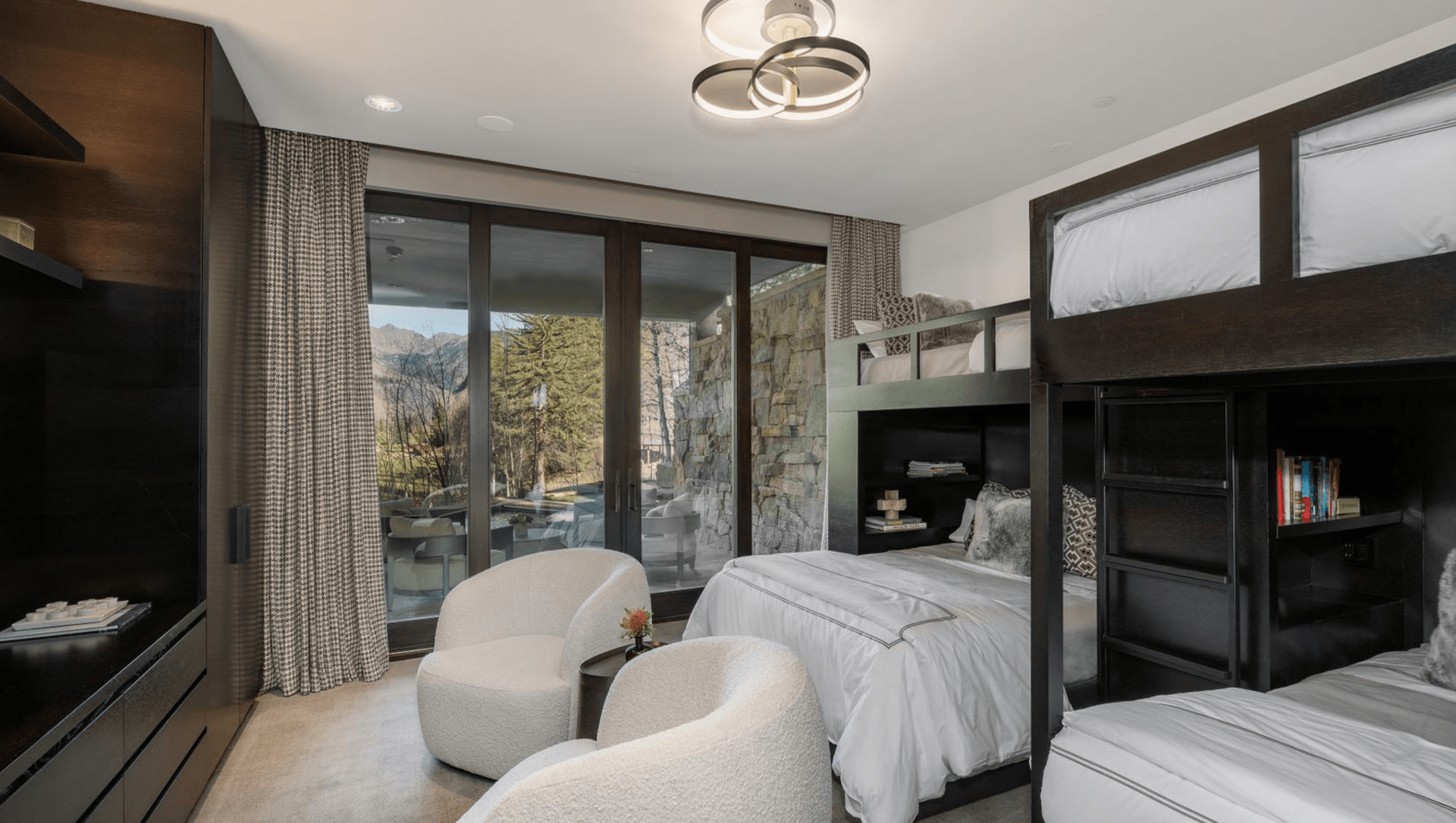 A bedroom with bunk beds , chairs and a television.