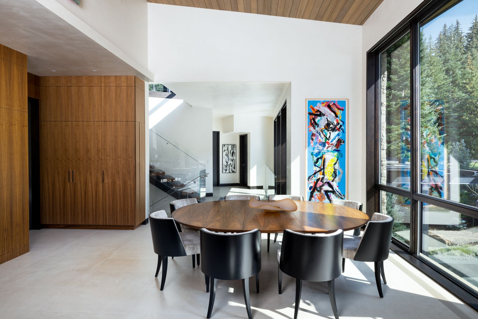 A dining room with a round table and chairs and a large window.