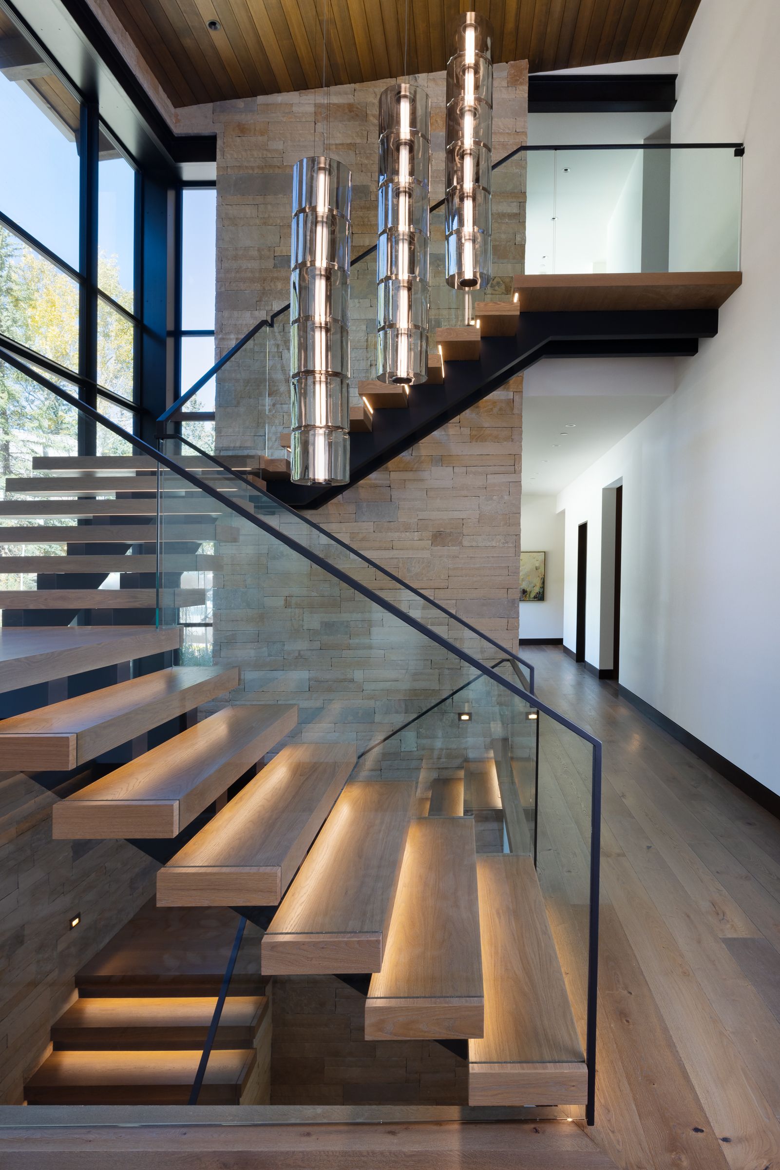 A modern staircase with a glass railing and wooden steps