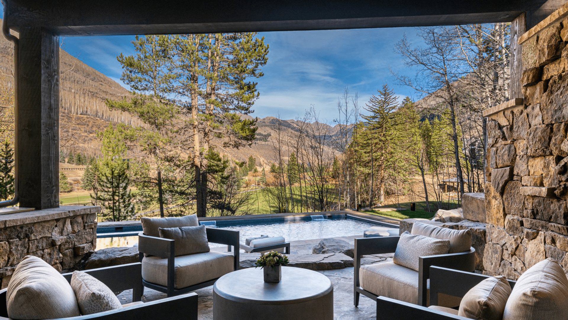 A patio with chairs , a table and a view of mountains.