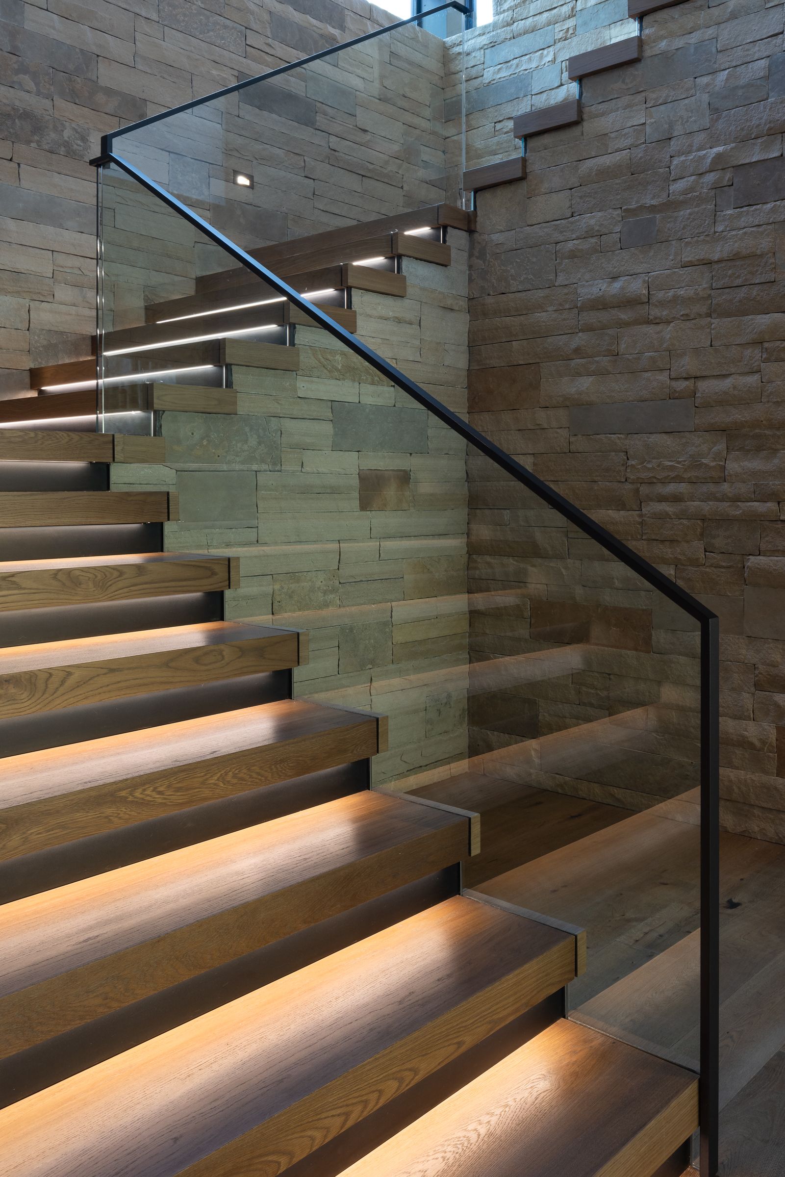 A staircase with a glass railing and wooden steps
