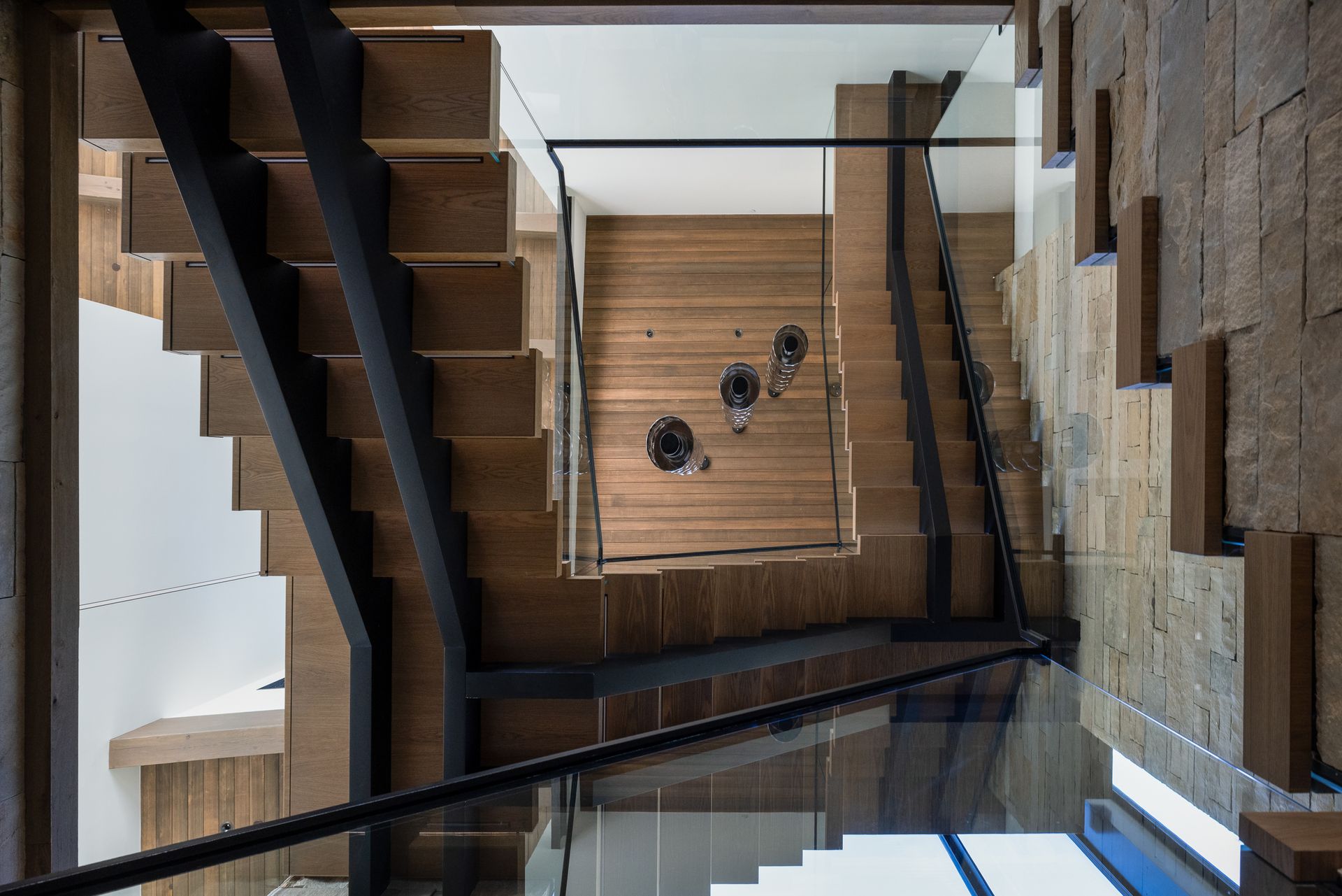 The stairs are made of wood and metal and have a glass railing.