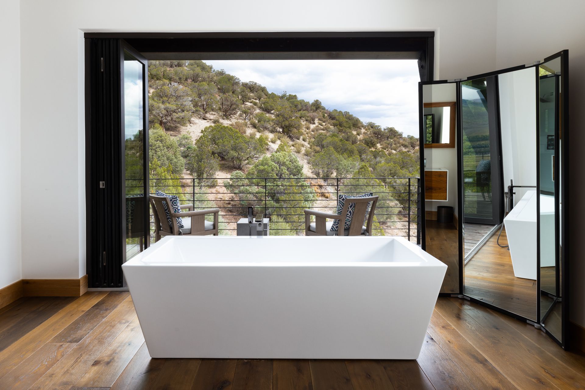 A bathroom with a bathtub and a large window with a view of a mountain.