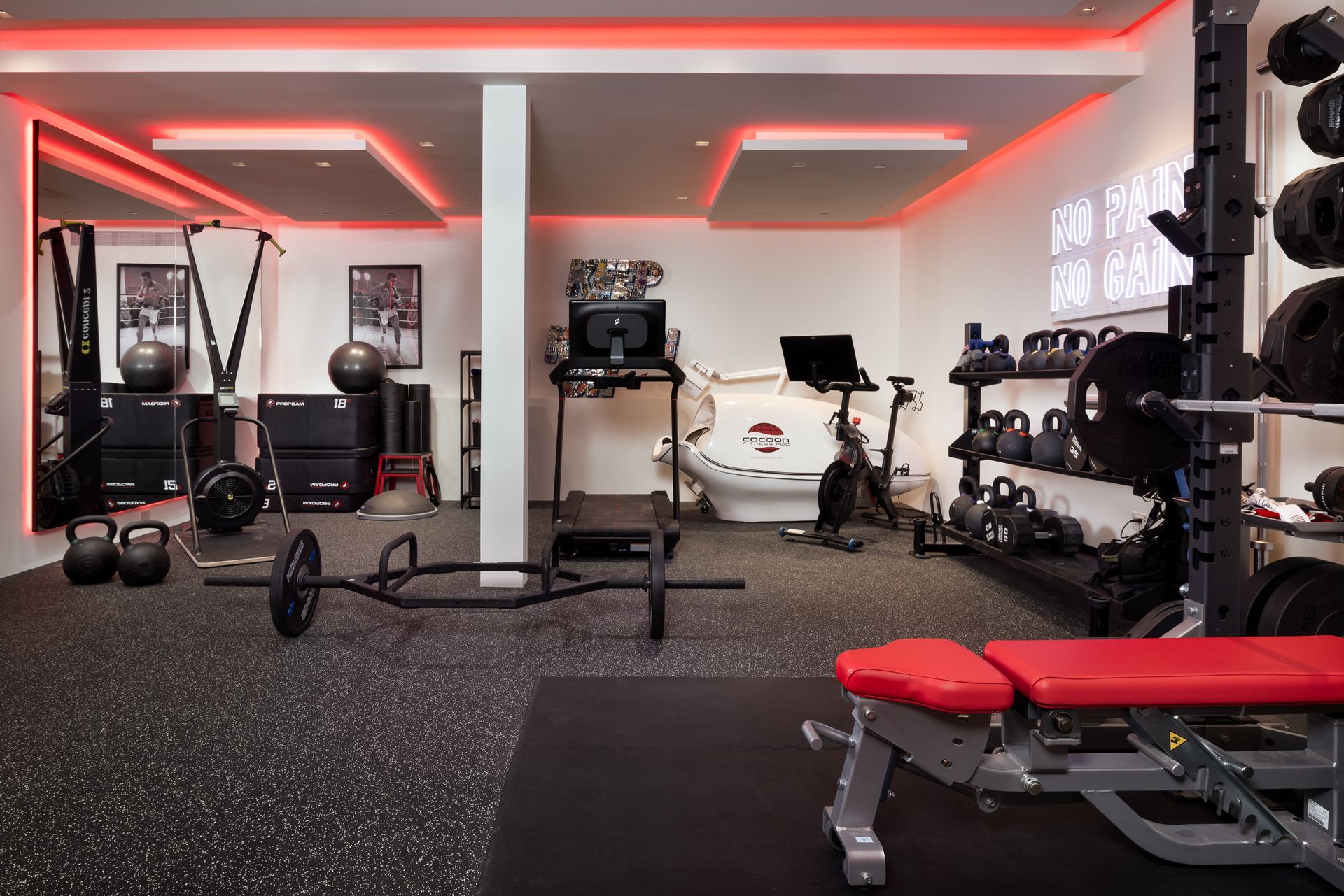 A large gym with a lot of equipment and a red bench.