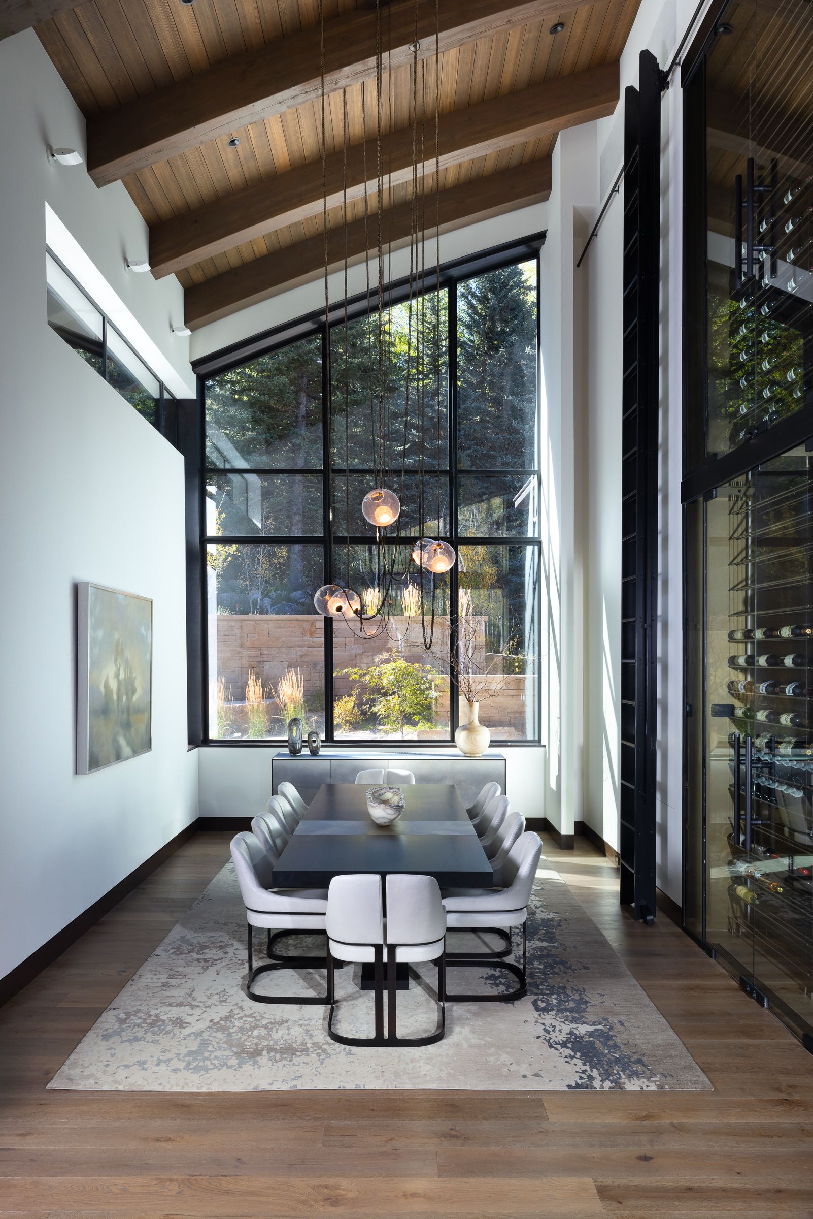 A dining room with a table and chairs and a large window.