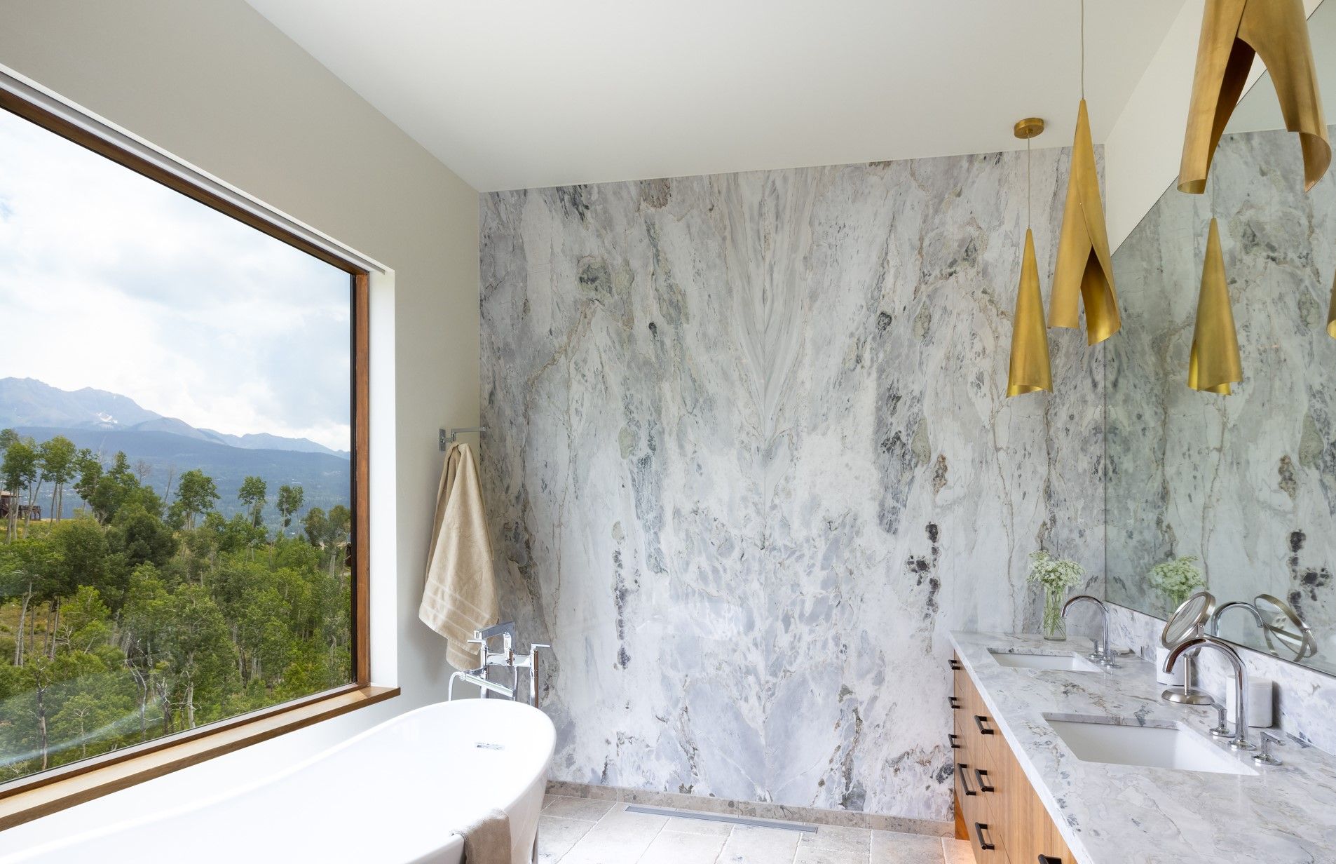 A bathroom with a tub , sinks , and a large window.