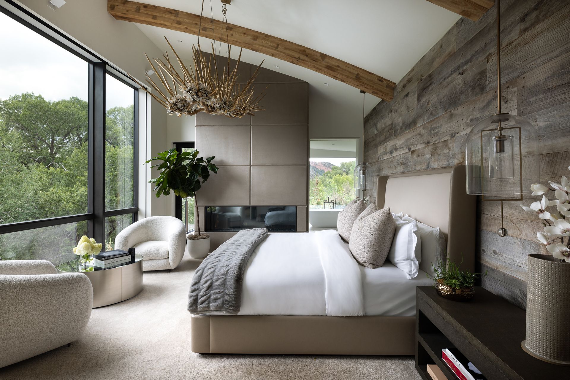 A bedroom with a large bed , chairs , and a fireplace.