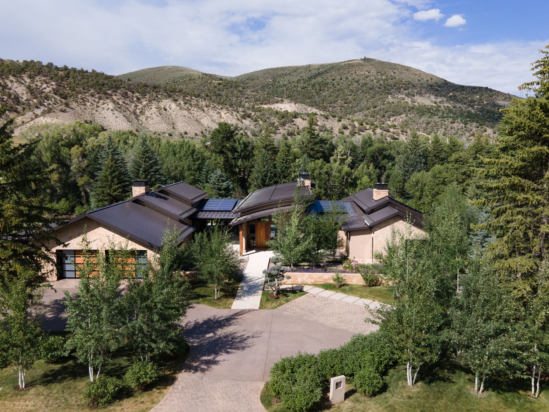 An aerial view of a large house surrounded by trees and mountains.