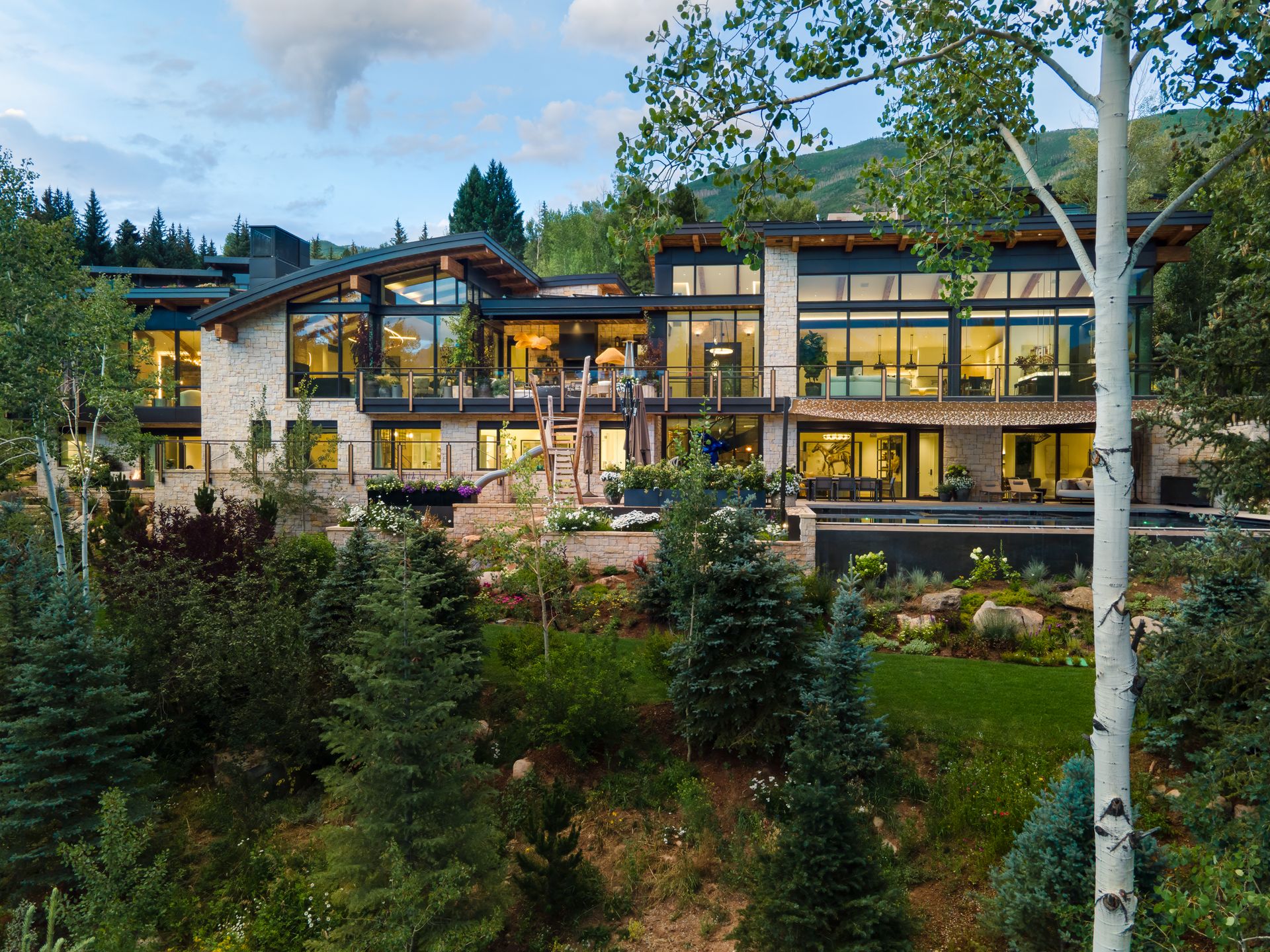 A large house is sitting on top of a hill surrounded by trees.