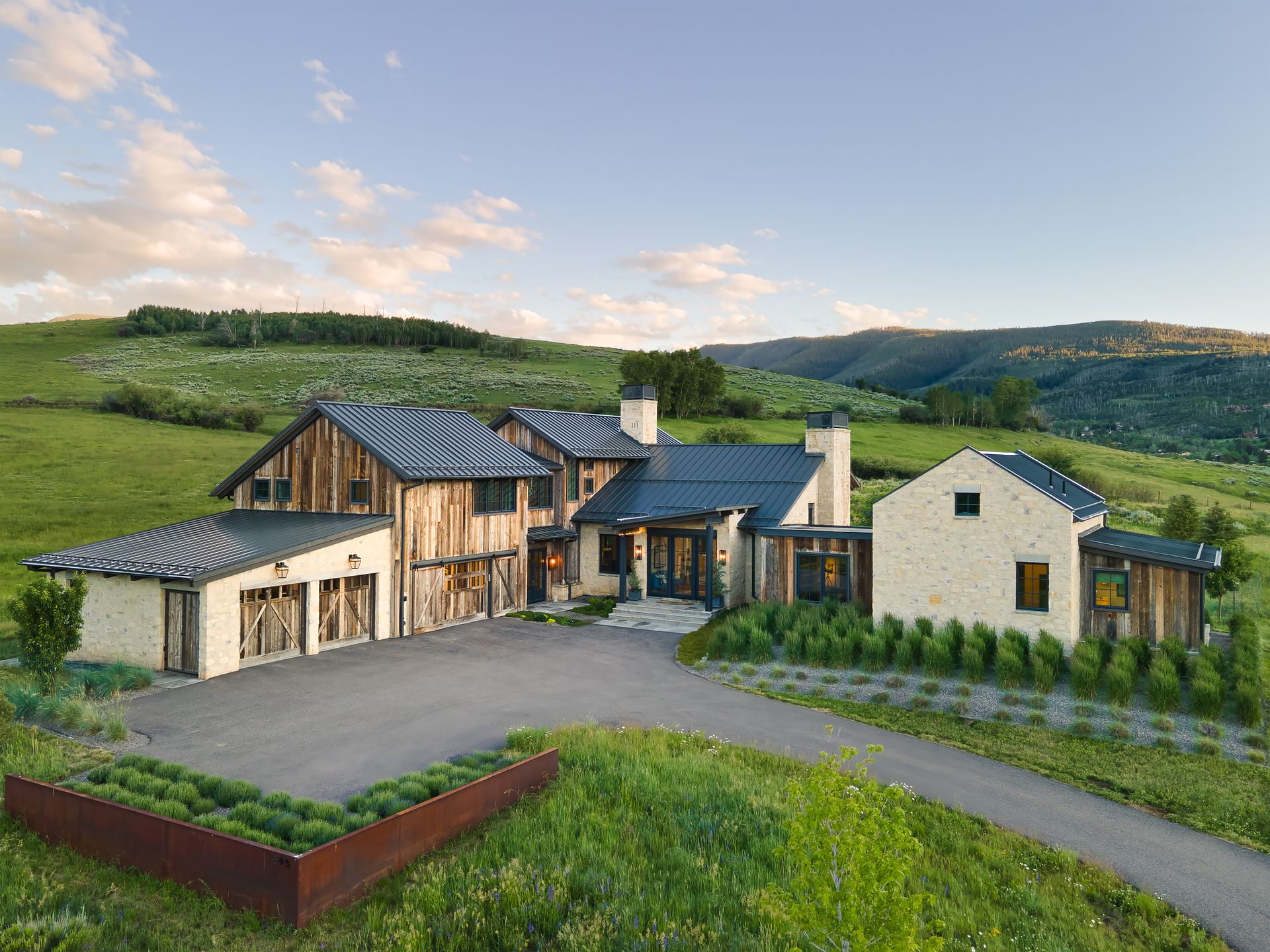 A large house is sitting on top of a grassy hill in the middle of a field.