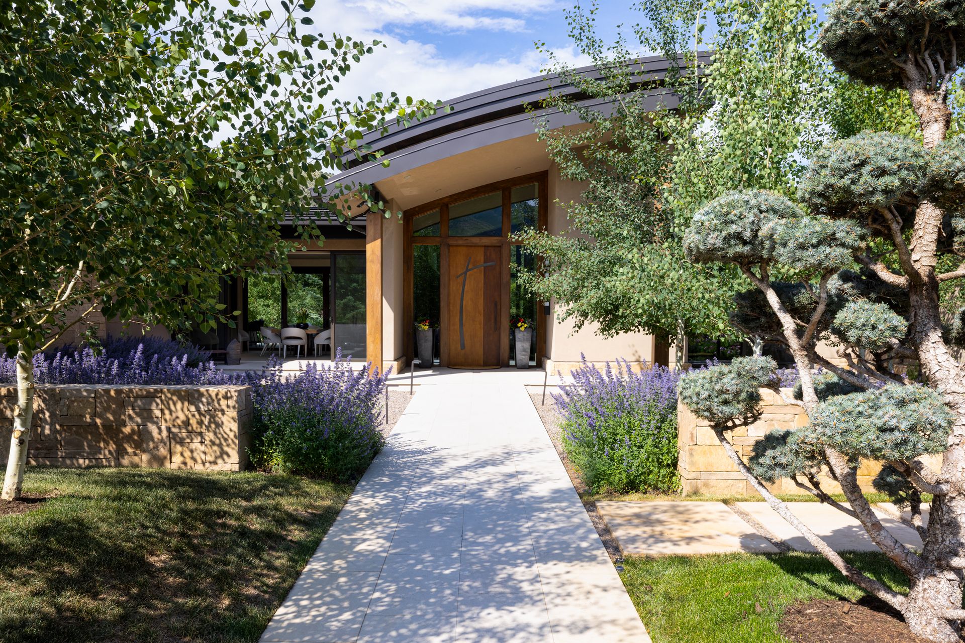 A house with a walkway leading to it and trees in front of it.