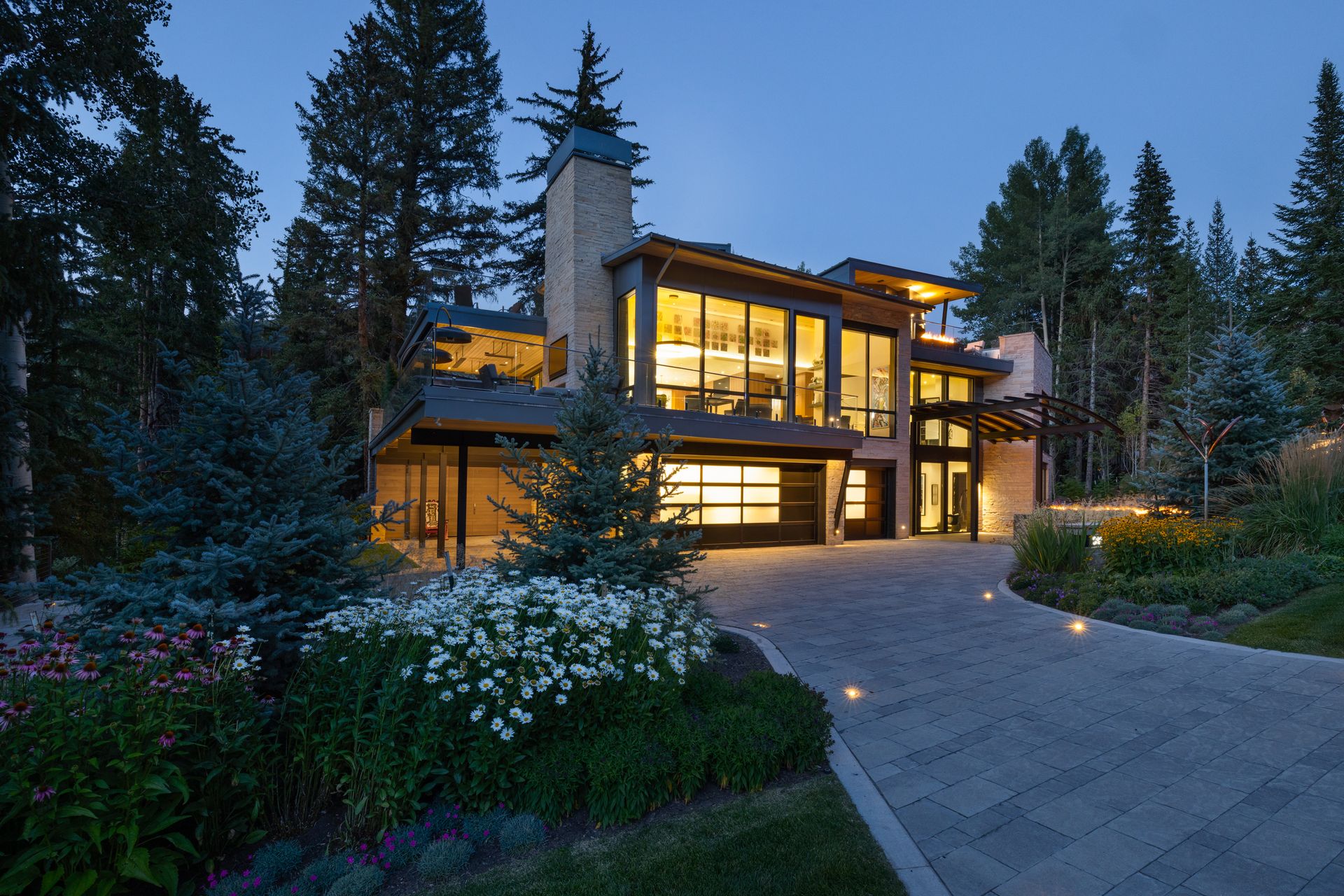 A large house with a lot of windows is surrounded by trees at night.