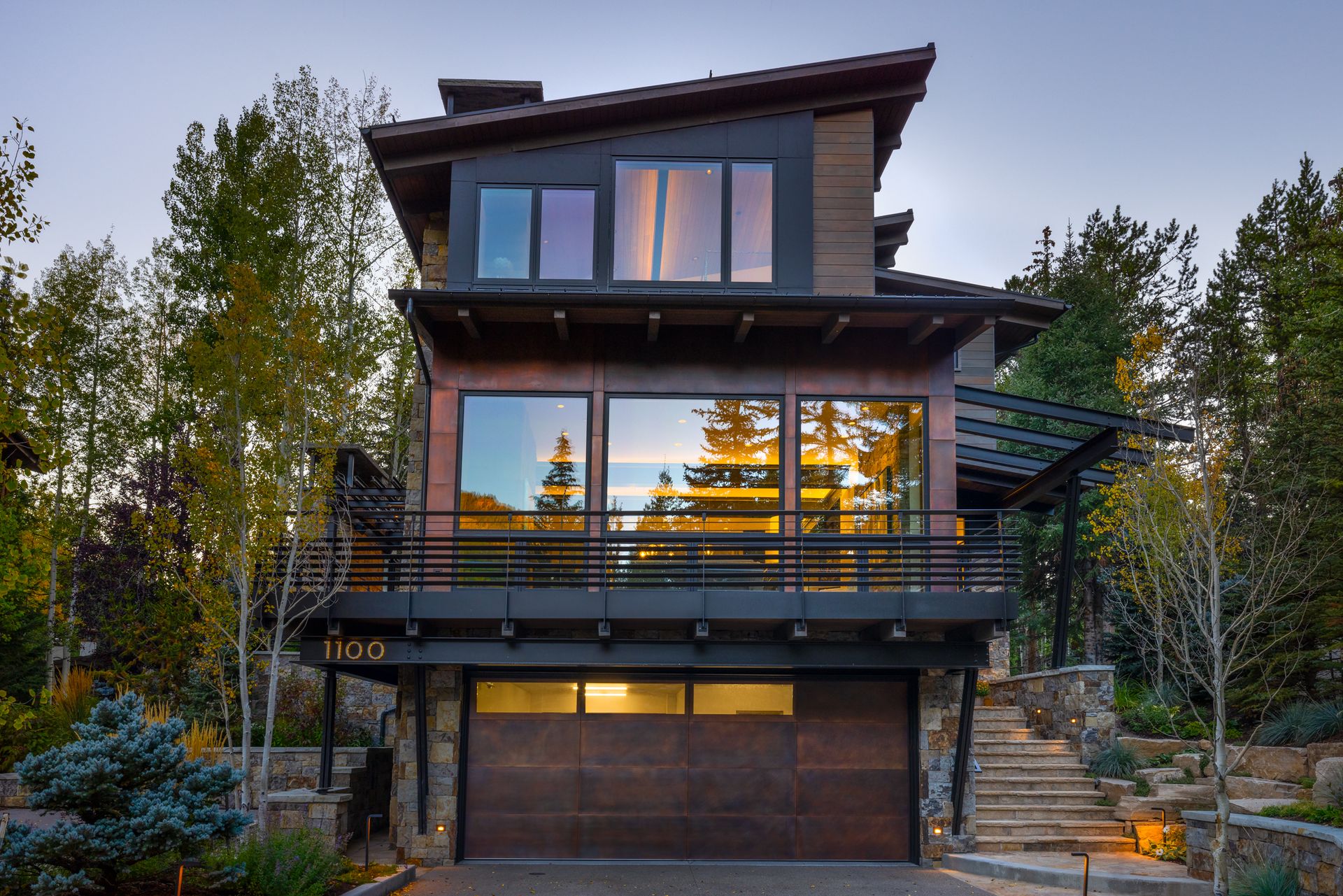 A modern house with a large garage and stairs leading up to it.
