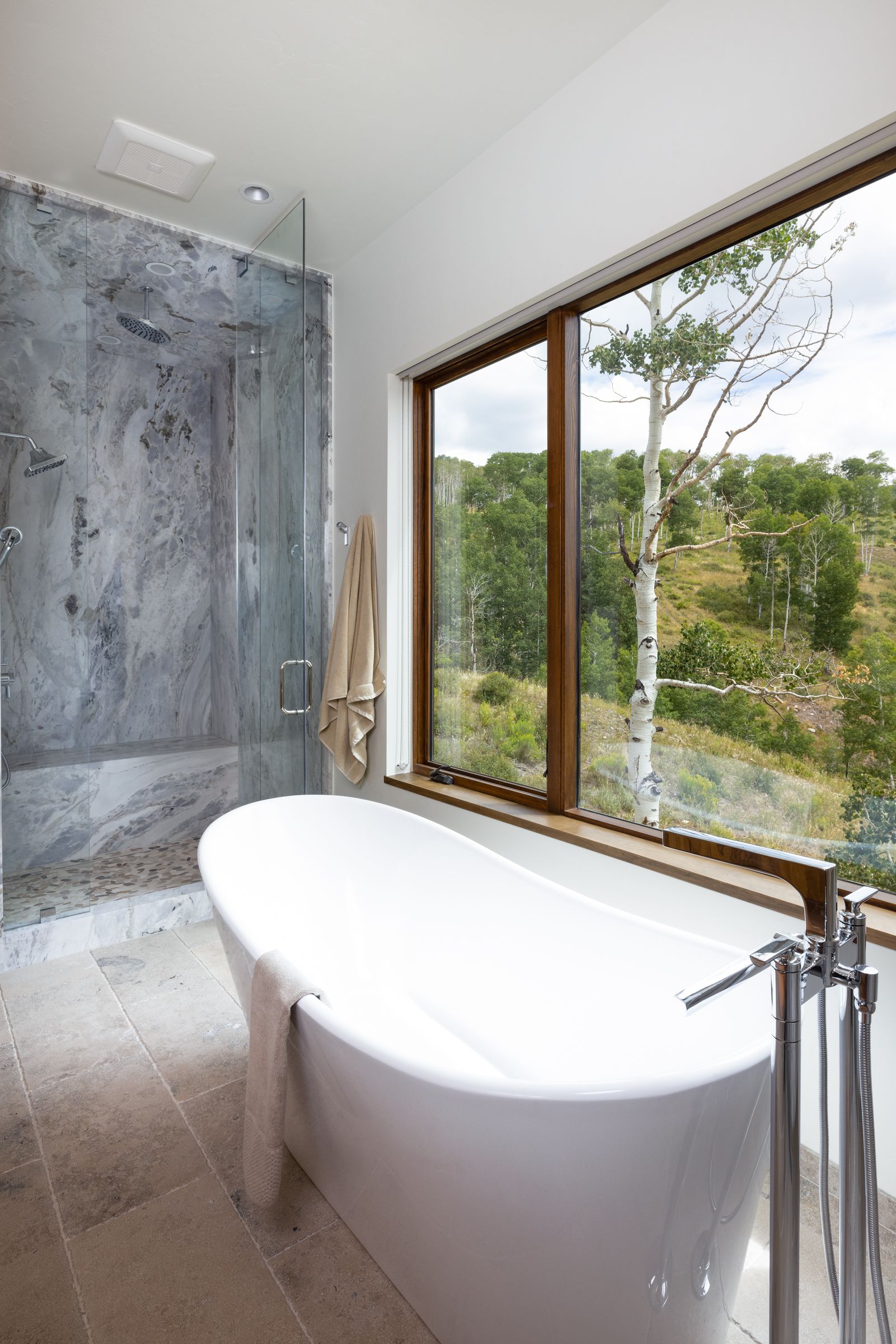 A bathroom with a tub , shower , and large window.