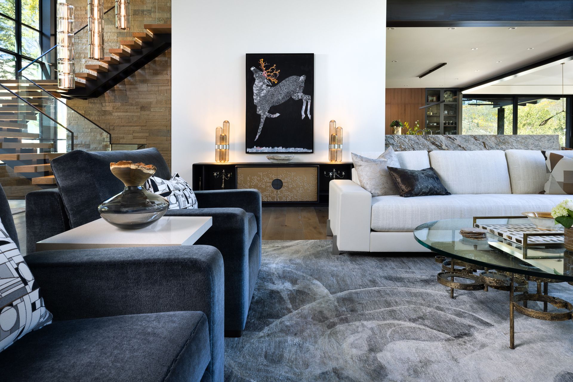 A living room with a couch , chairs , coffee table and stairs.