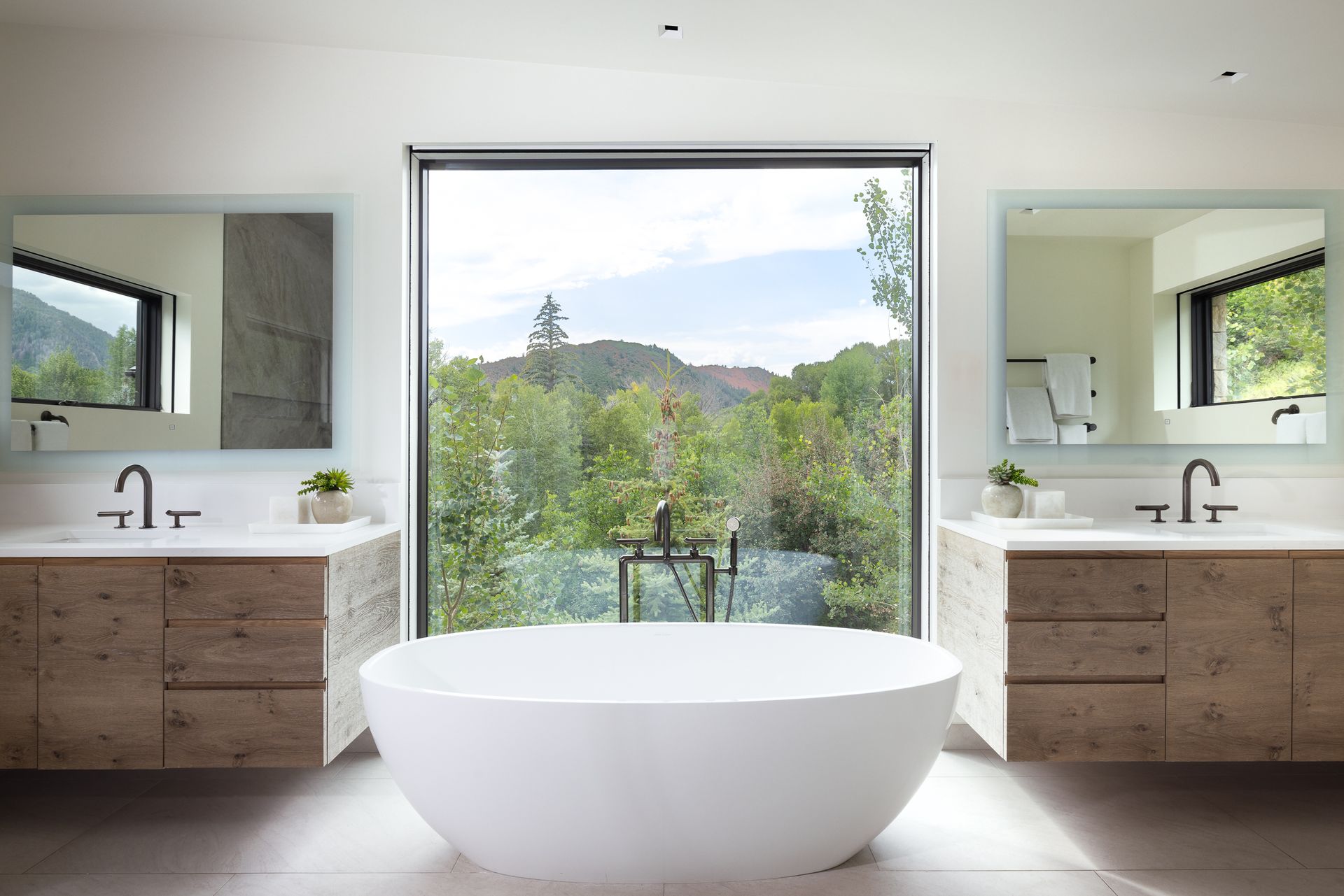 A bathroom with two sinks , a tub and a large window.