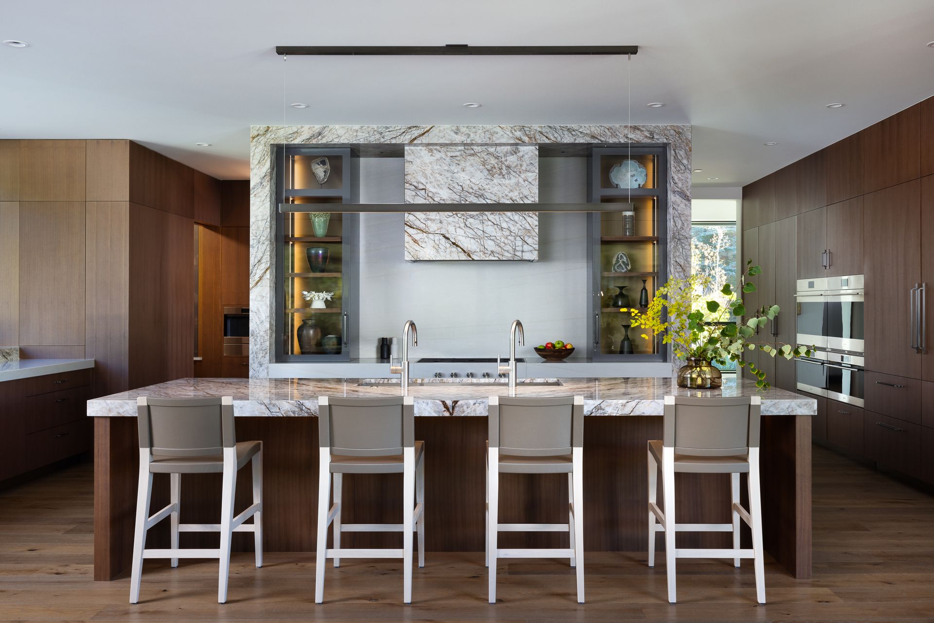 A kitchen with a large island , stools and a stove.