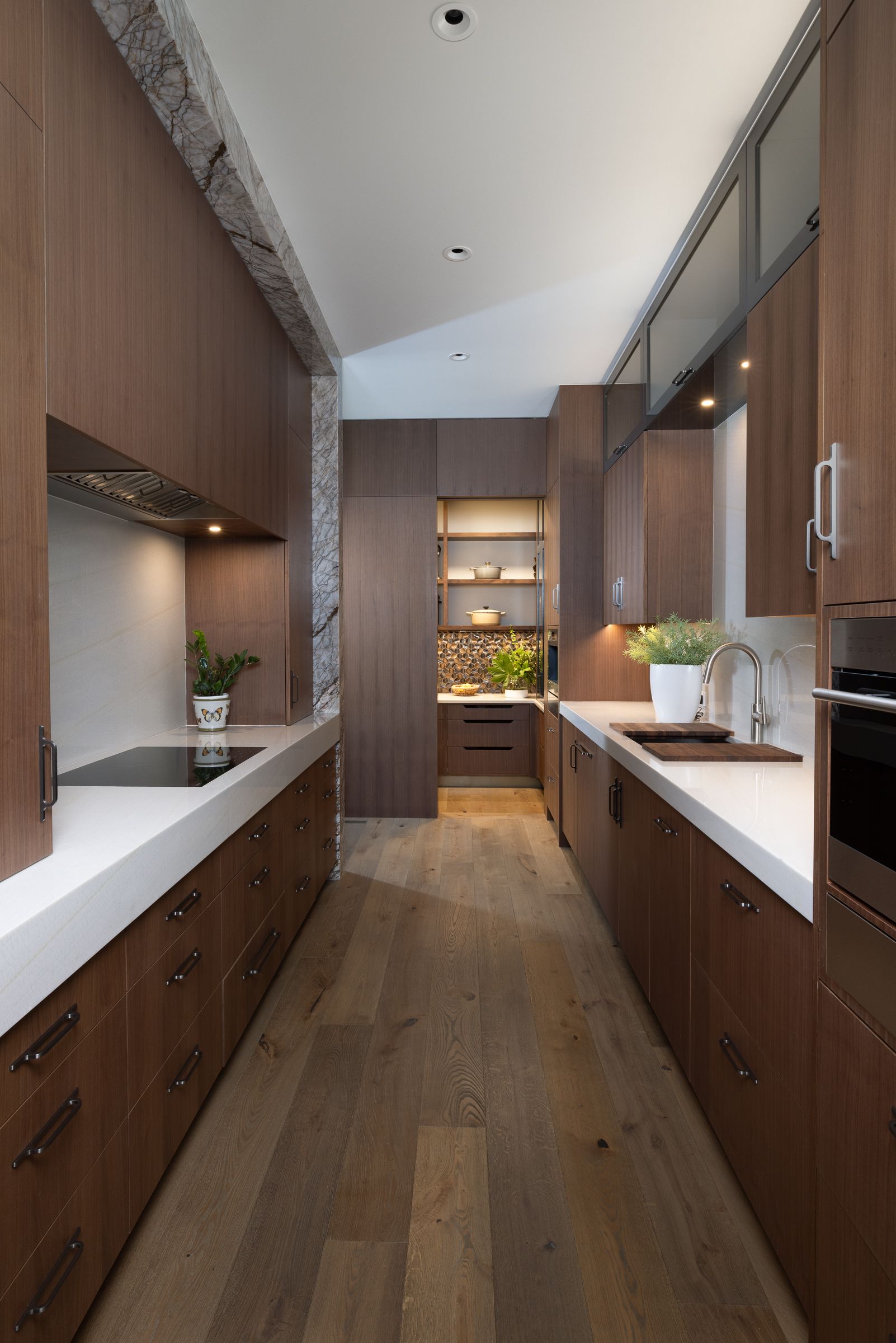 A long kitchen with wooden cabinets and white counter tops