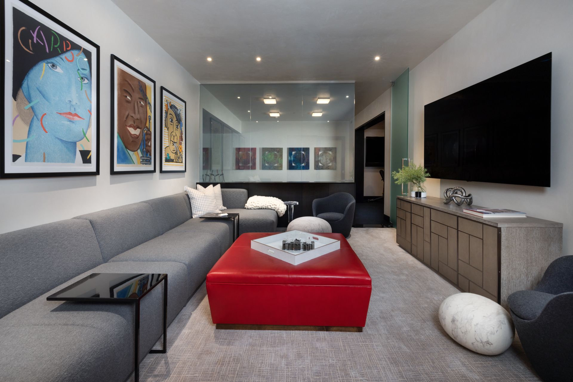 A living room with a couch and a red ottoman