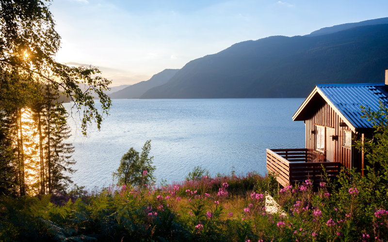 A small house sits on the shore of a lake