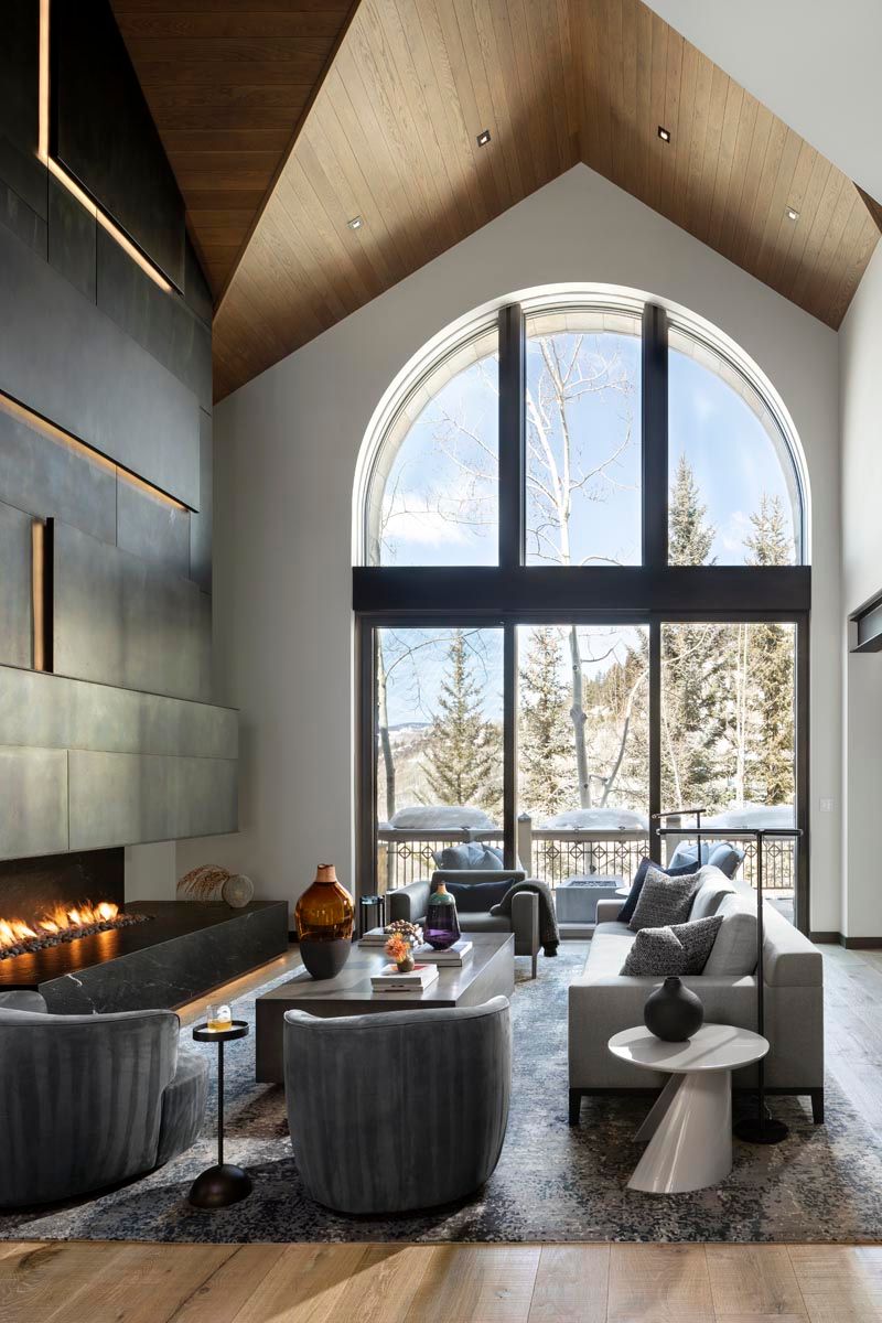 A living room with a fireplace , couch , chairs and a large window.