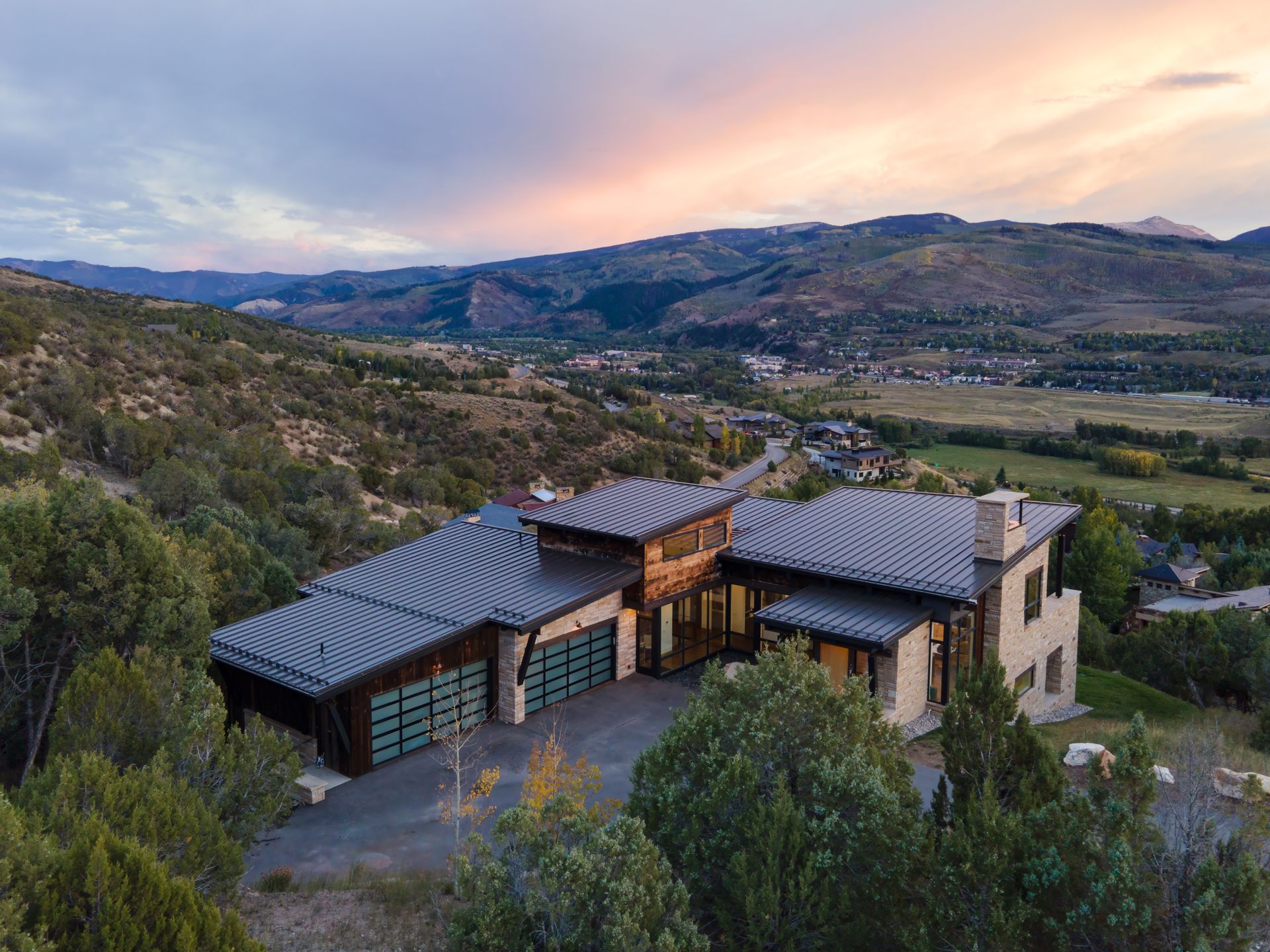 An aerial view of a large house sitting on top of a hill surrounded by trees.