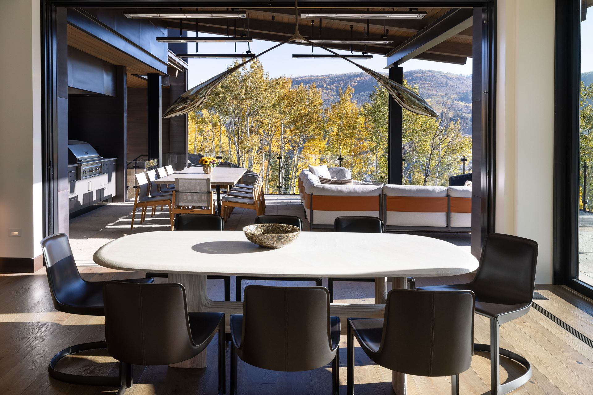 A dining room with a table and chairs and a view of the mountains.