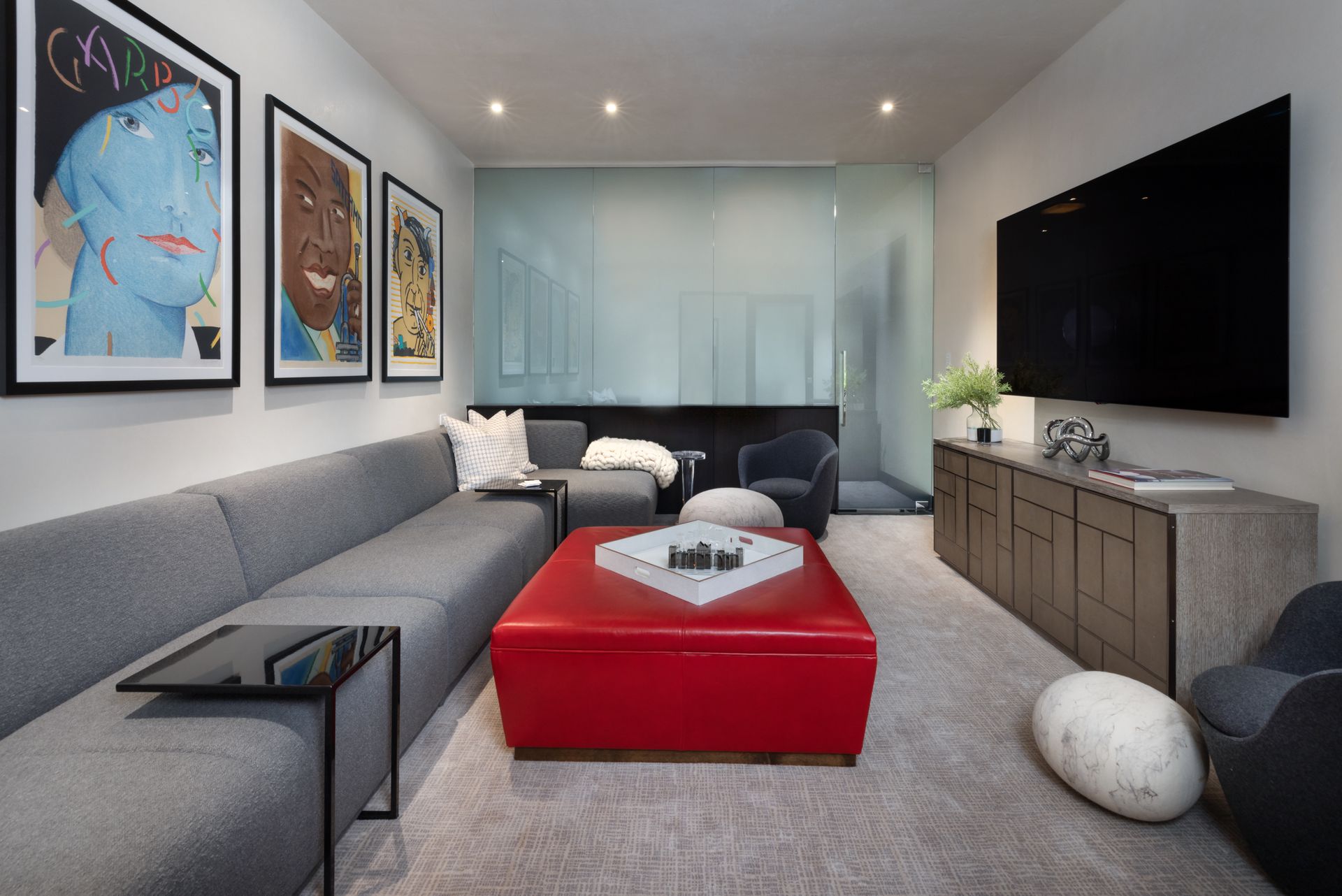 A living room with a couch and a red ottoman