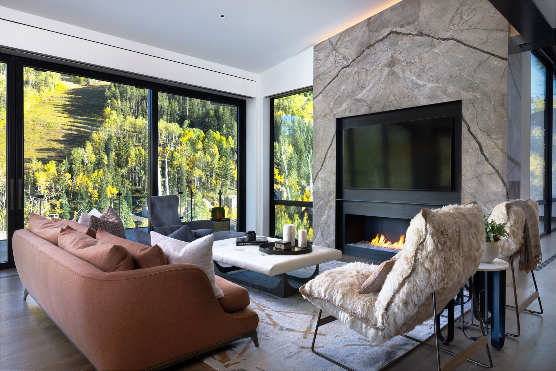 A living room with a couch , chairs , fireplace and television.