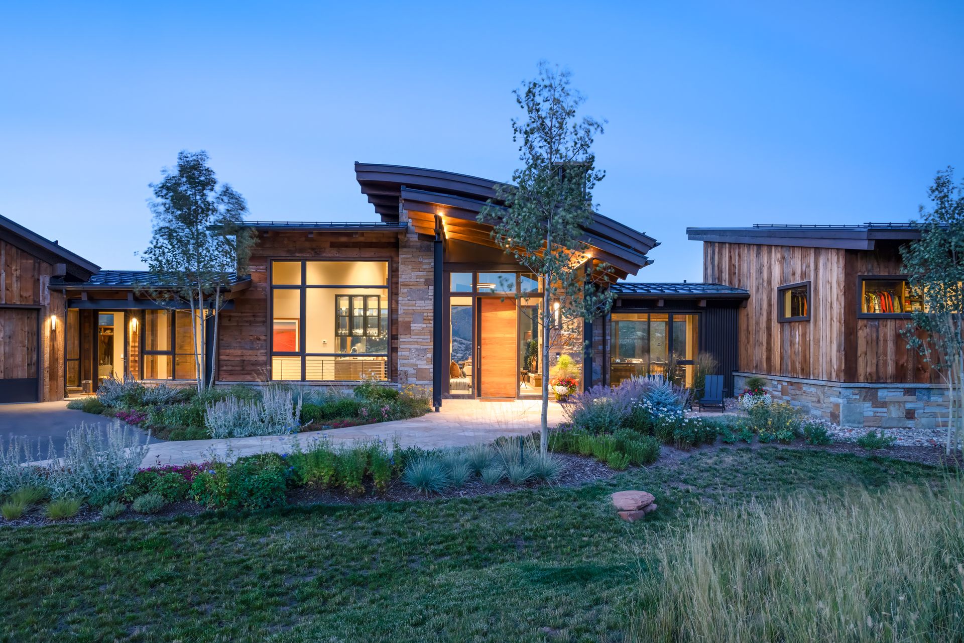 A large wooden house with a lot of windows is sitting on top of a lush green field.