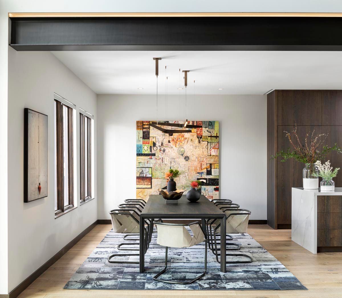 A dining room with a table and chairs and a painting on the wall