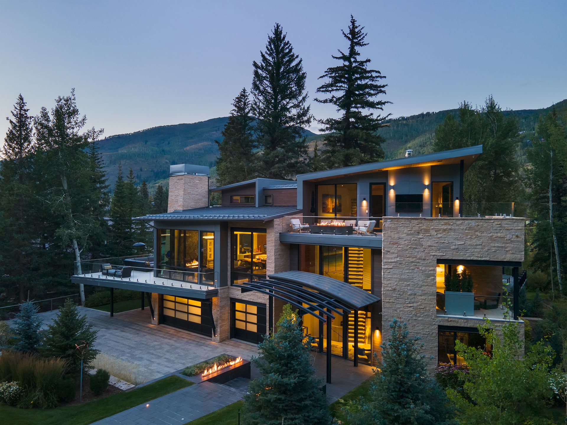 An aerial view of a large house surrounded by trees and mountains