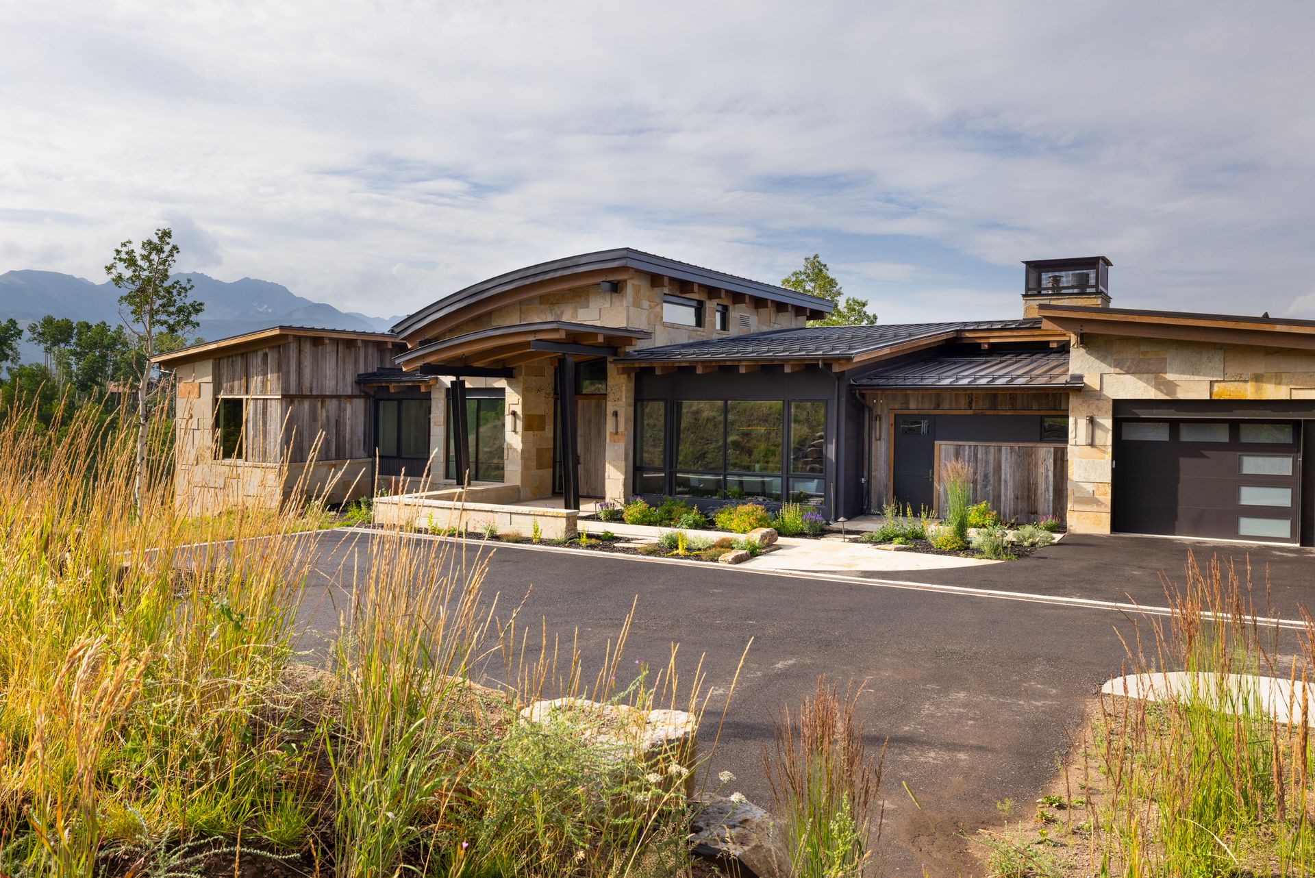 A large house is sitting on the side of a road surrounded by tall grass.