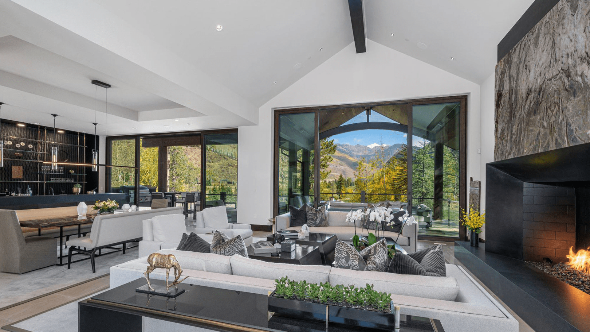 A living room filled with furniture and a fireplace with a view of the mountains.