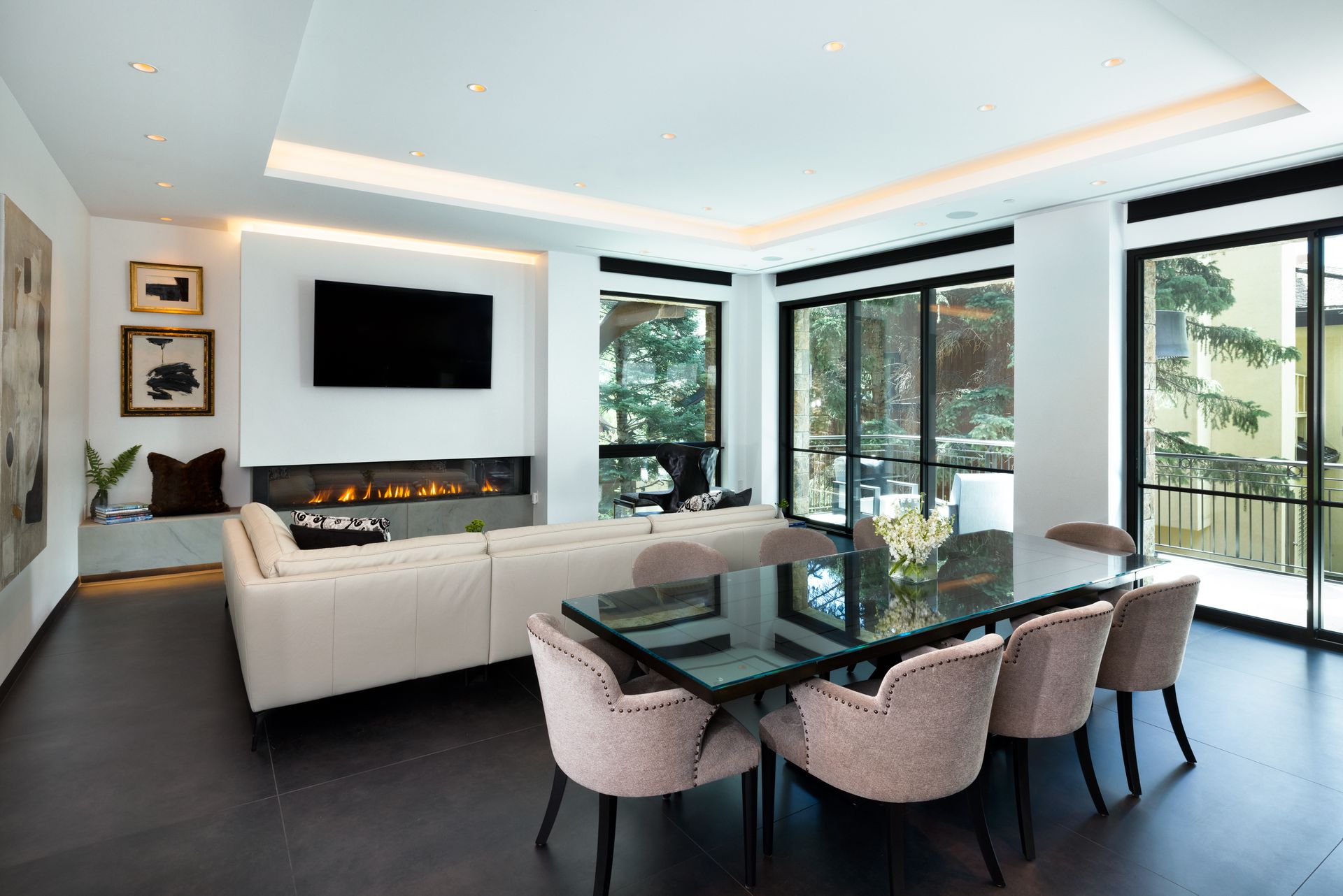 A living room with a couch , table , chairs and a flat screen tv.