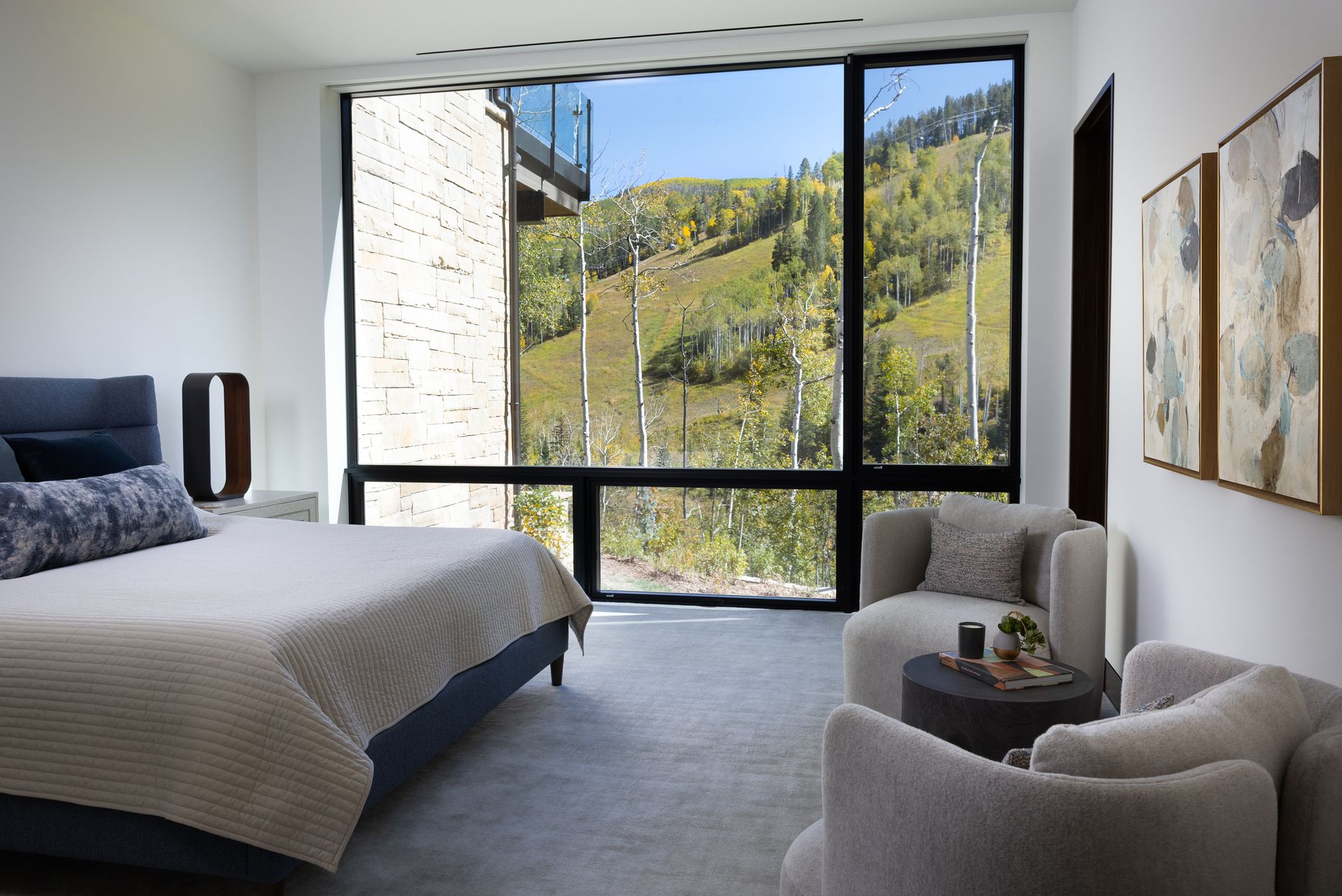 A bedroom with a large bed , chairs and a large window.