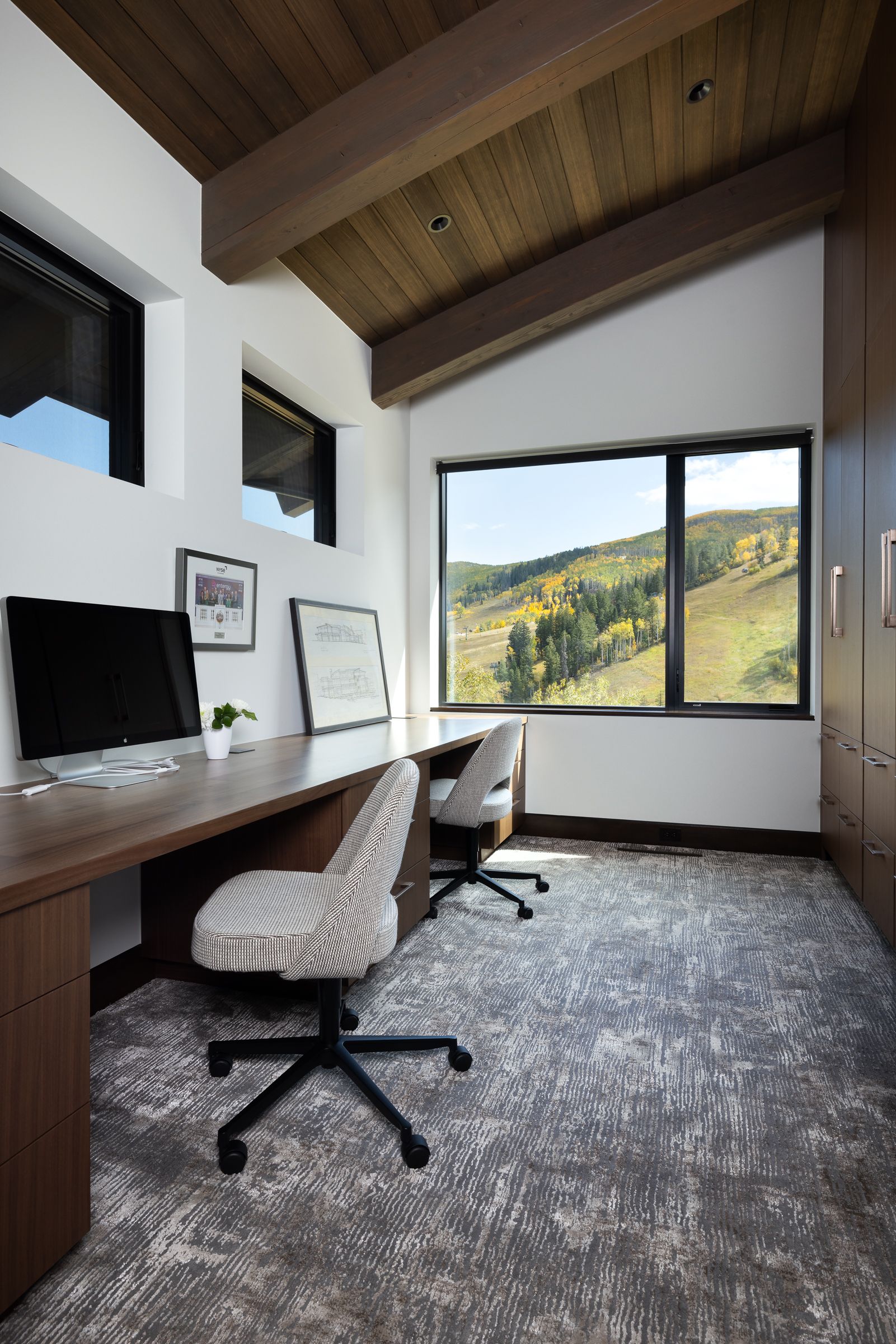 A home office with a desk , chairs and a computer.